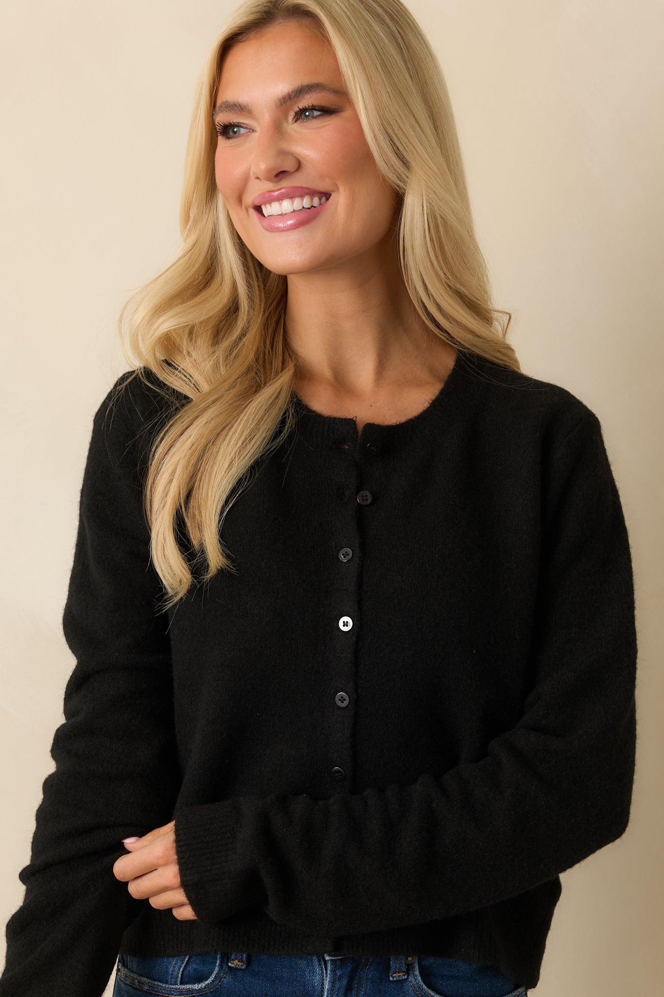View of the black cardigan’s sweater knit and ribbed hemline with a soft, relaxed texture.
