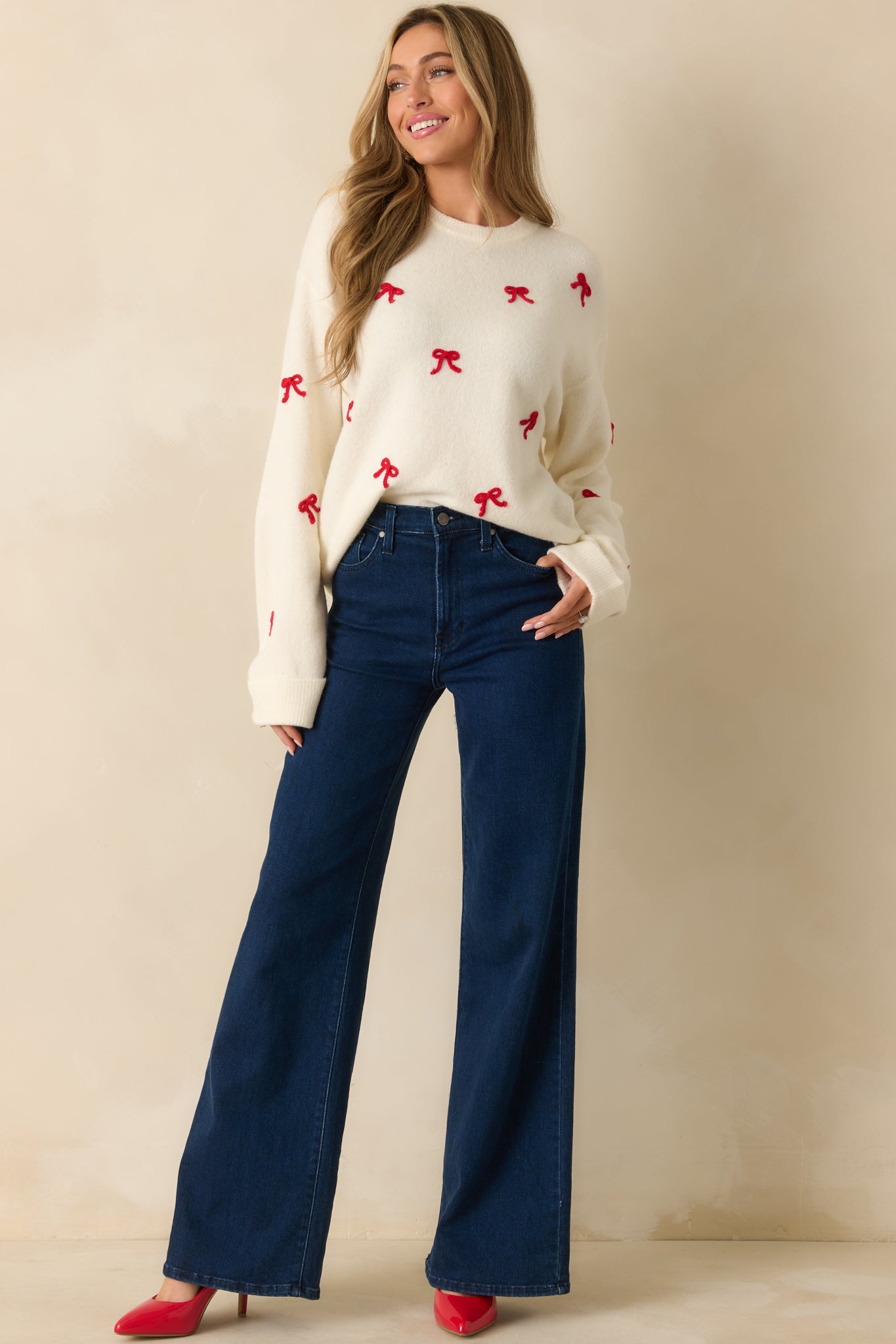 Relaxed-fit white sweater with soft knit fabric and scattered red bow embroidery for a cheerful, festive style.