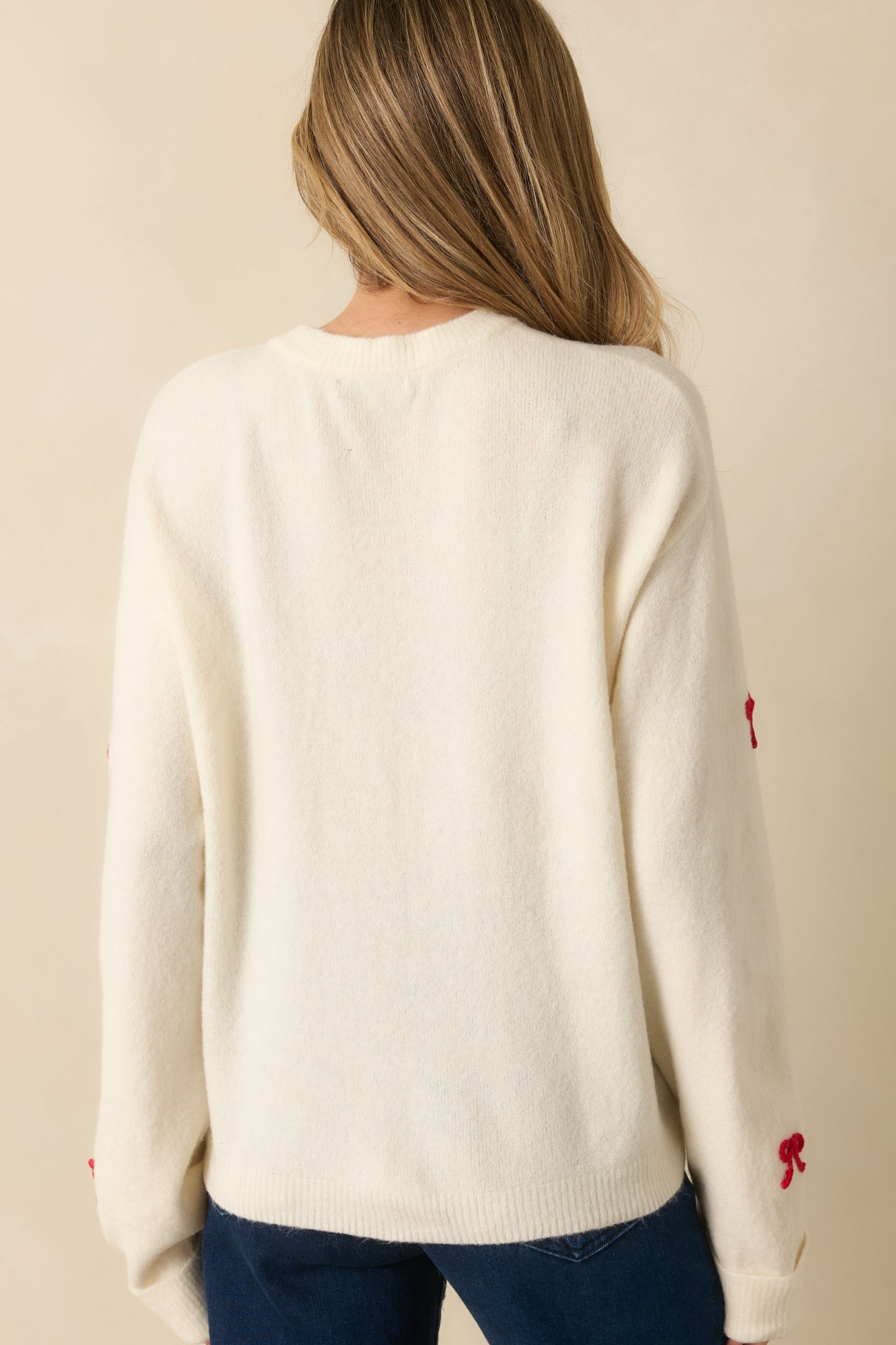 Rear view of white pullover sweater, showing relaxed fit, long sleeves, and smooth knit finish.