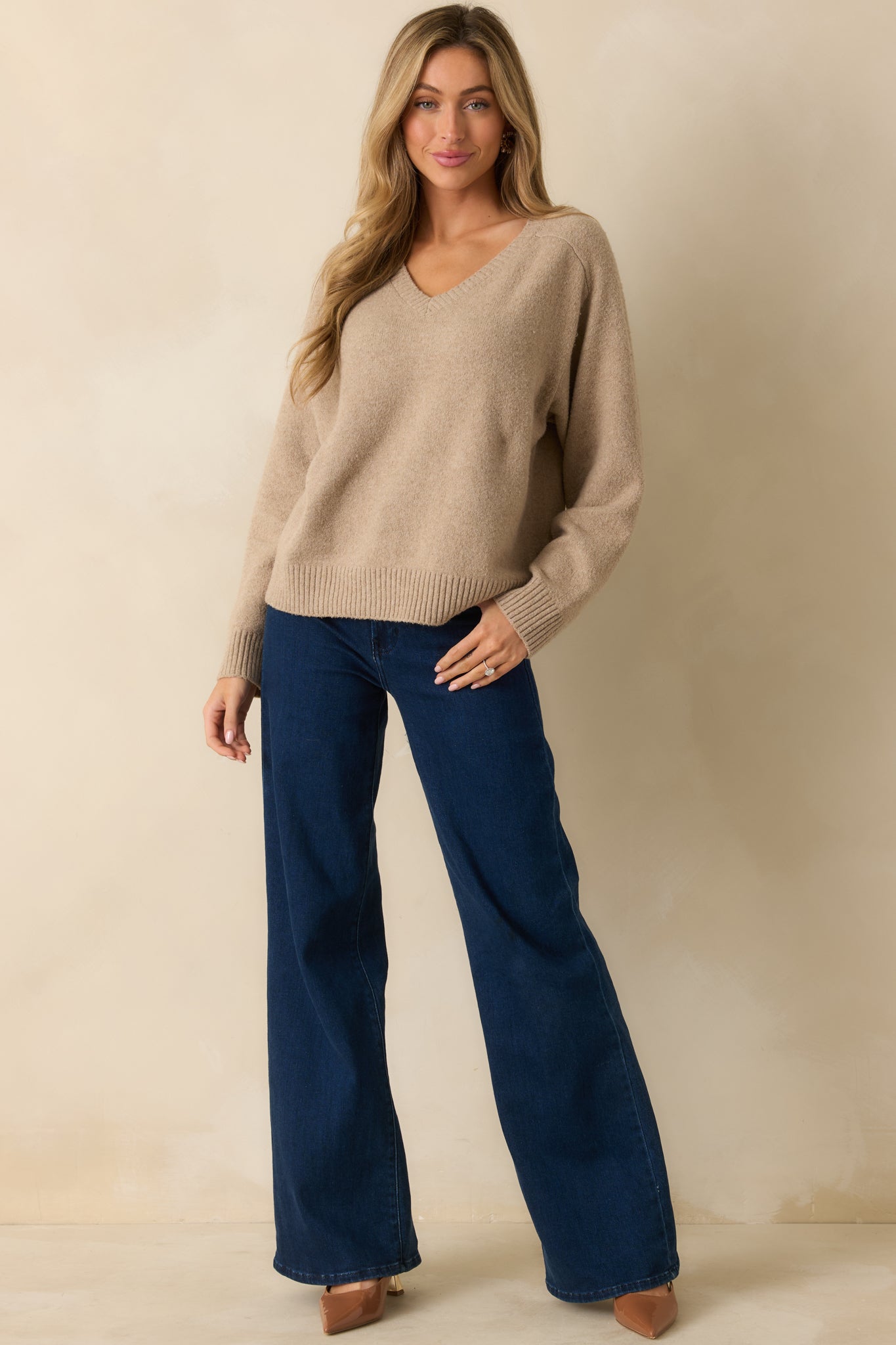 Beige knit sweater highlighting a straight hemline and gently textured mid-weight fabric.