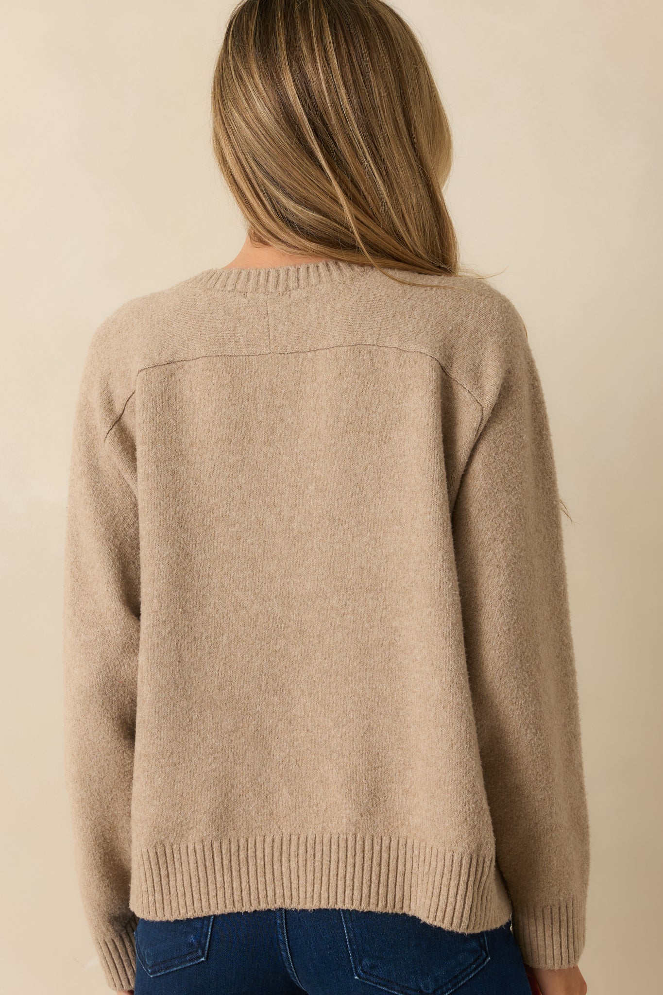Rear view of the beige V-neck sweater displaying dropped shoulders and clean straight hem.