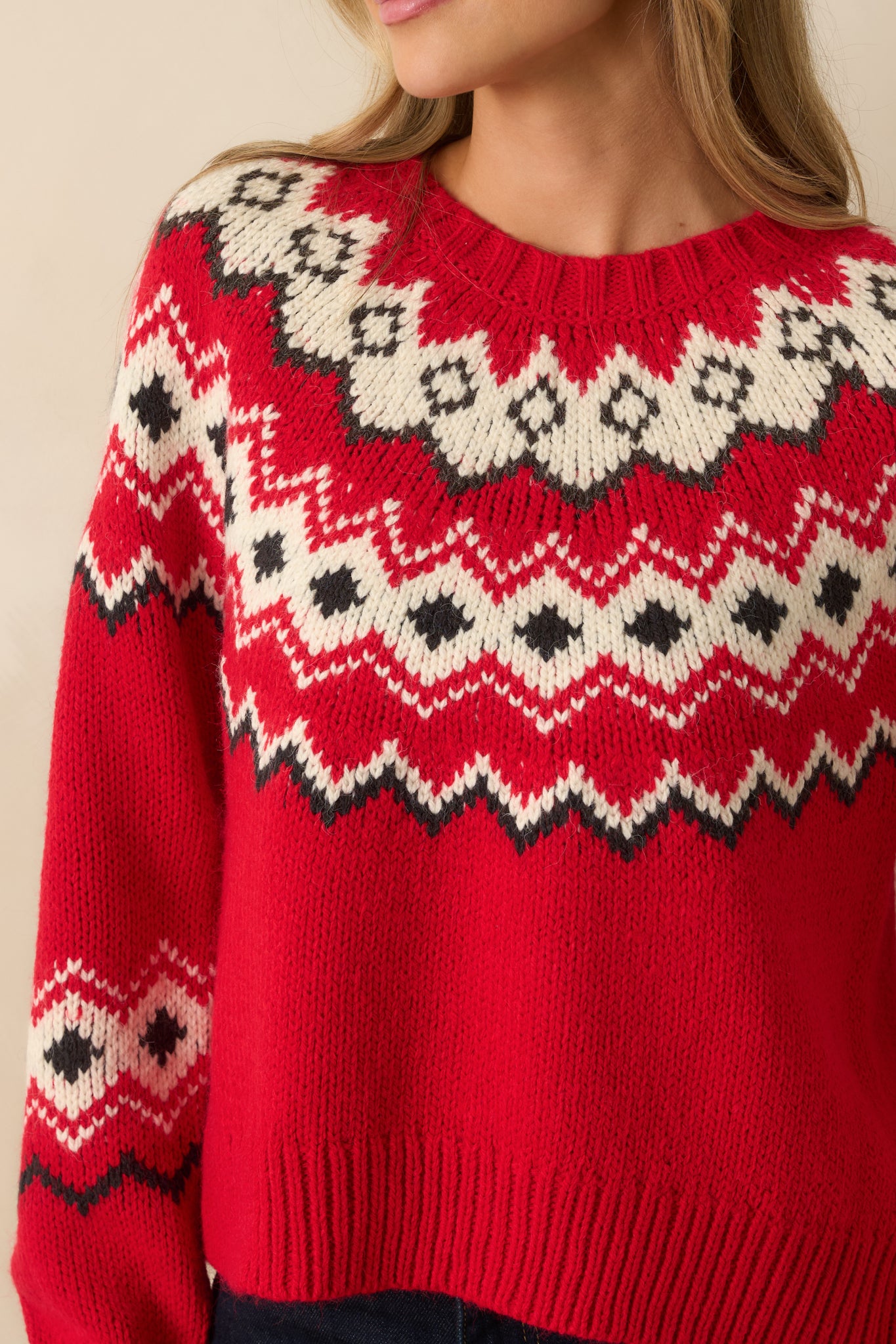 Detailed close-up of red knit fabric with fair isle-inspired pattern, showing texture and festive design.