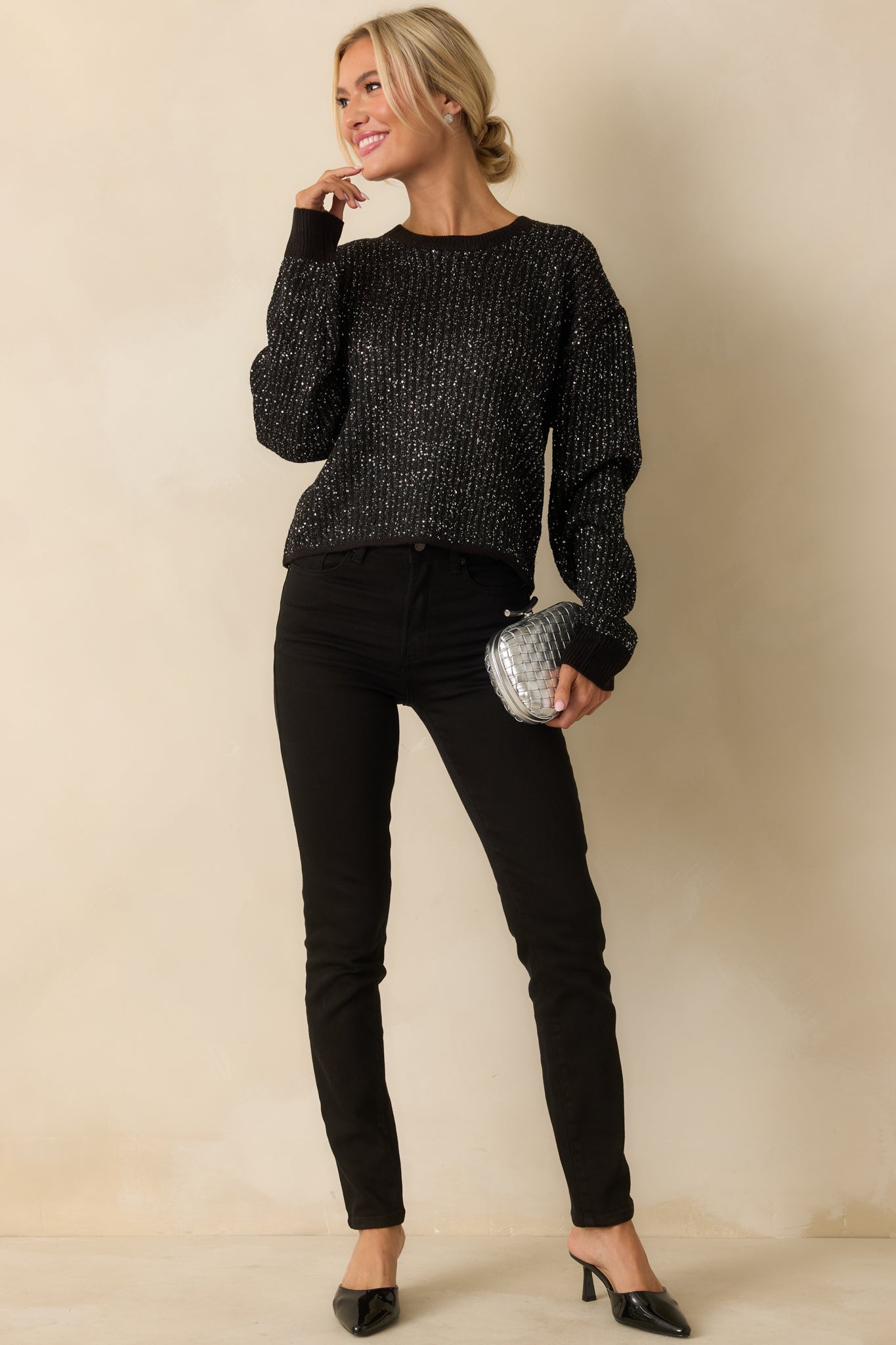 Full frontal shot emphasizing the long sleeves and casual fit of the black ribbed knit sweater.