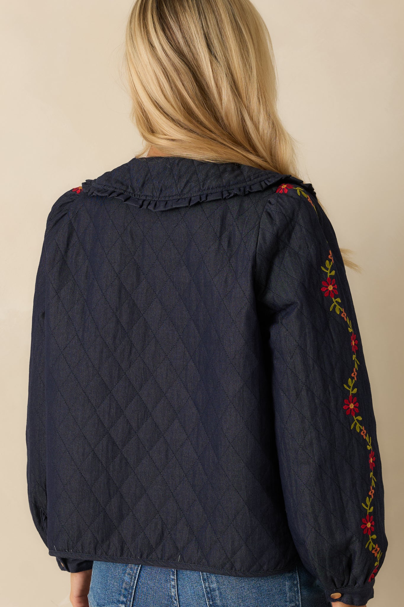 Rear view of the dark indigo quilted jacket displaying the diamond-quilt pattern and clean back finish.
