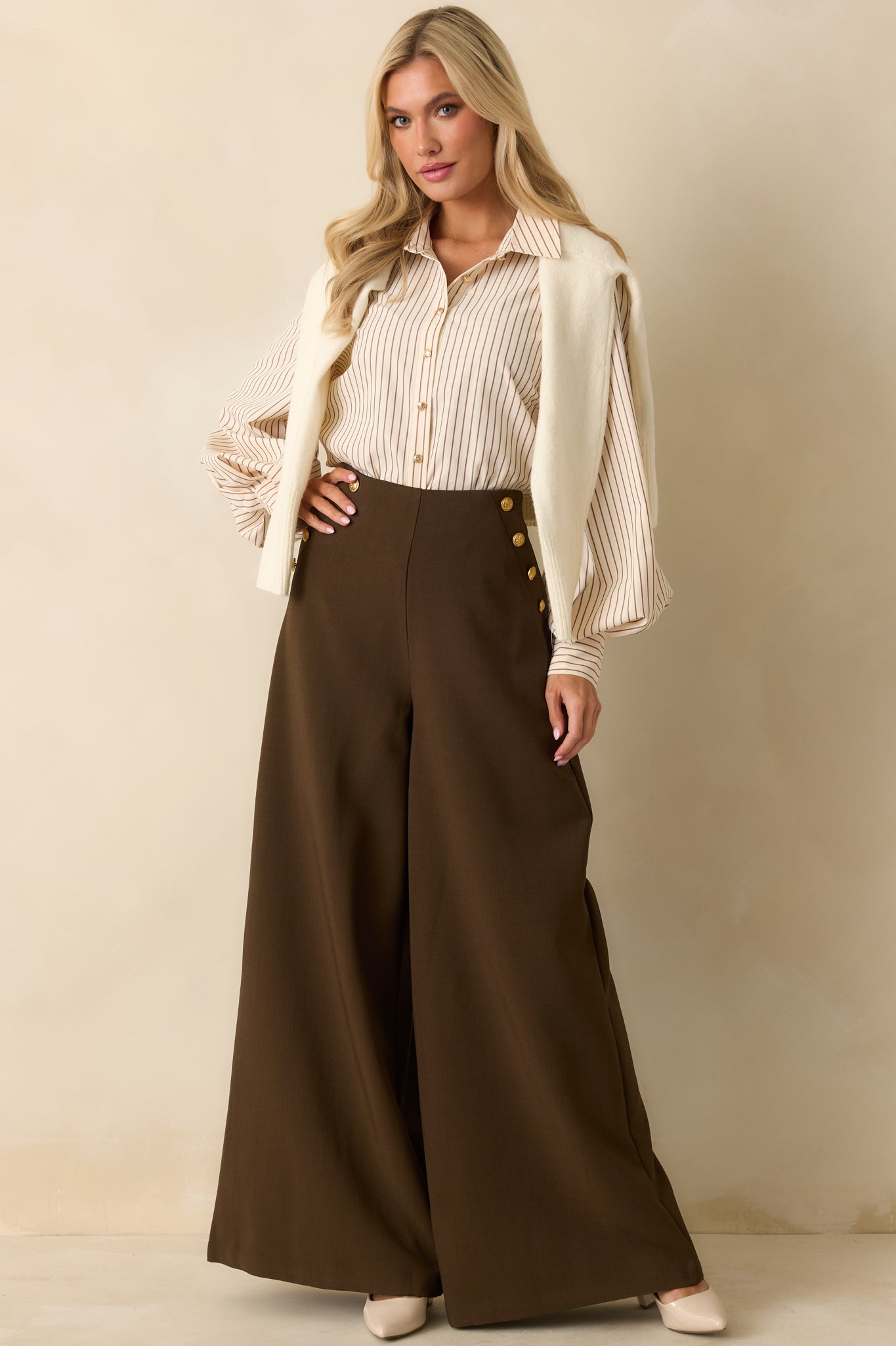 The pinstriped ivory blouse highlights its relaxed shape and polished gold buttons.
