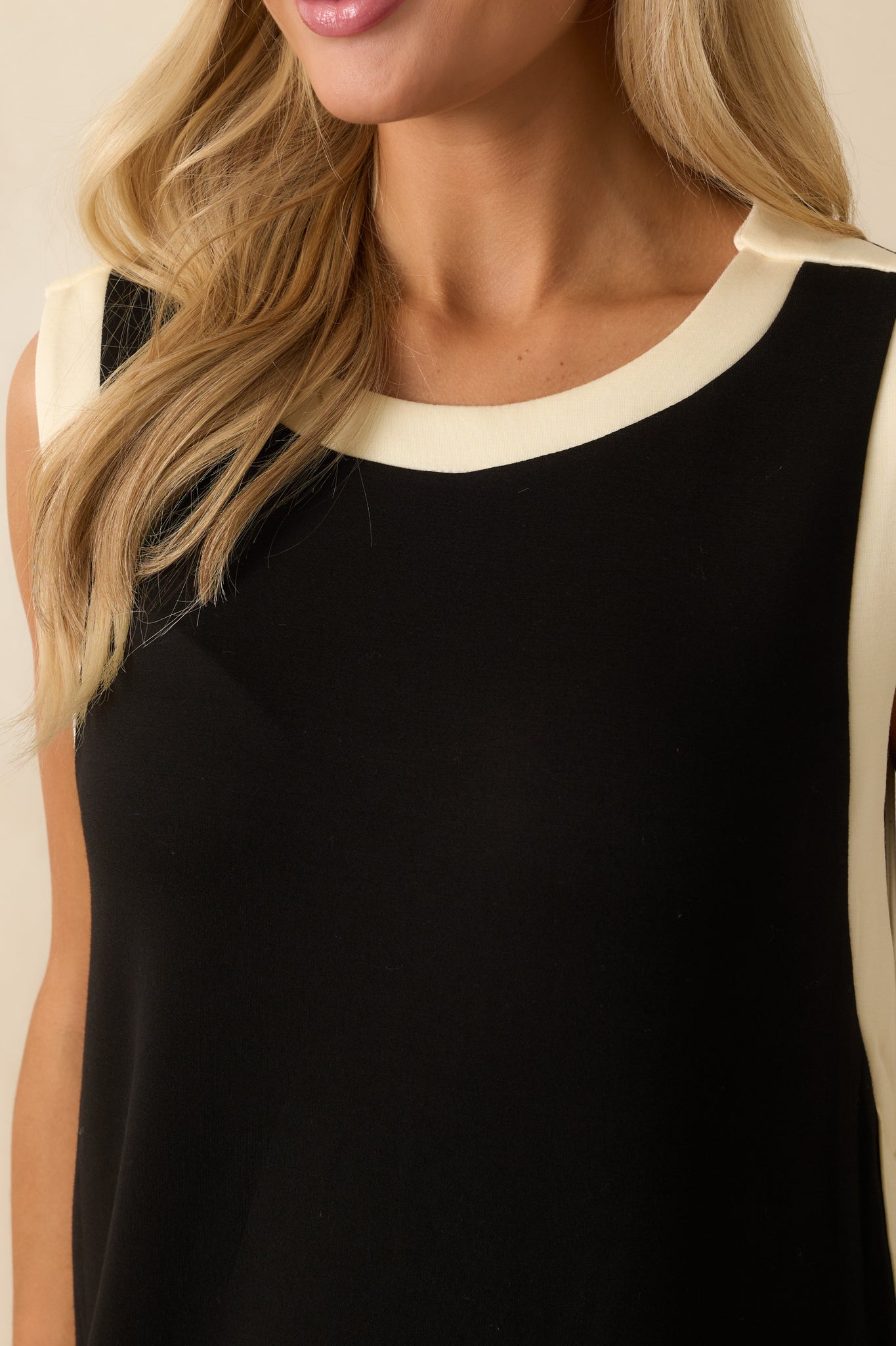 Close-up of the neckline and armhole area showing contrast ivory trim and soft jersey knit texture.