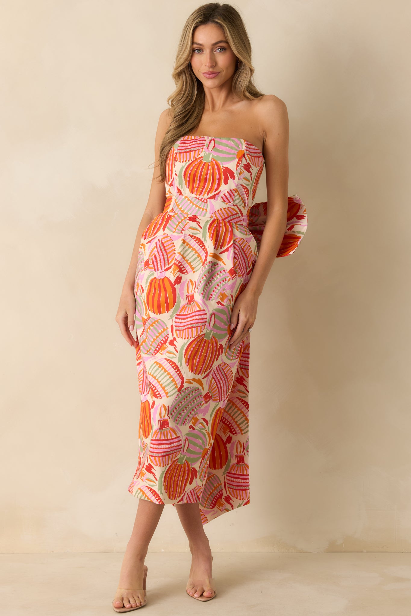 The midi dress displays its vibrant multicolor pattern and asymmetric hem with a smooth, structured fit.