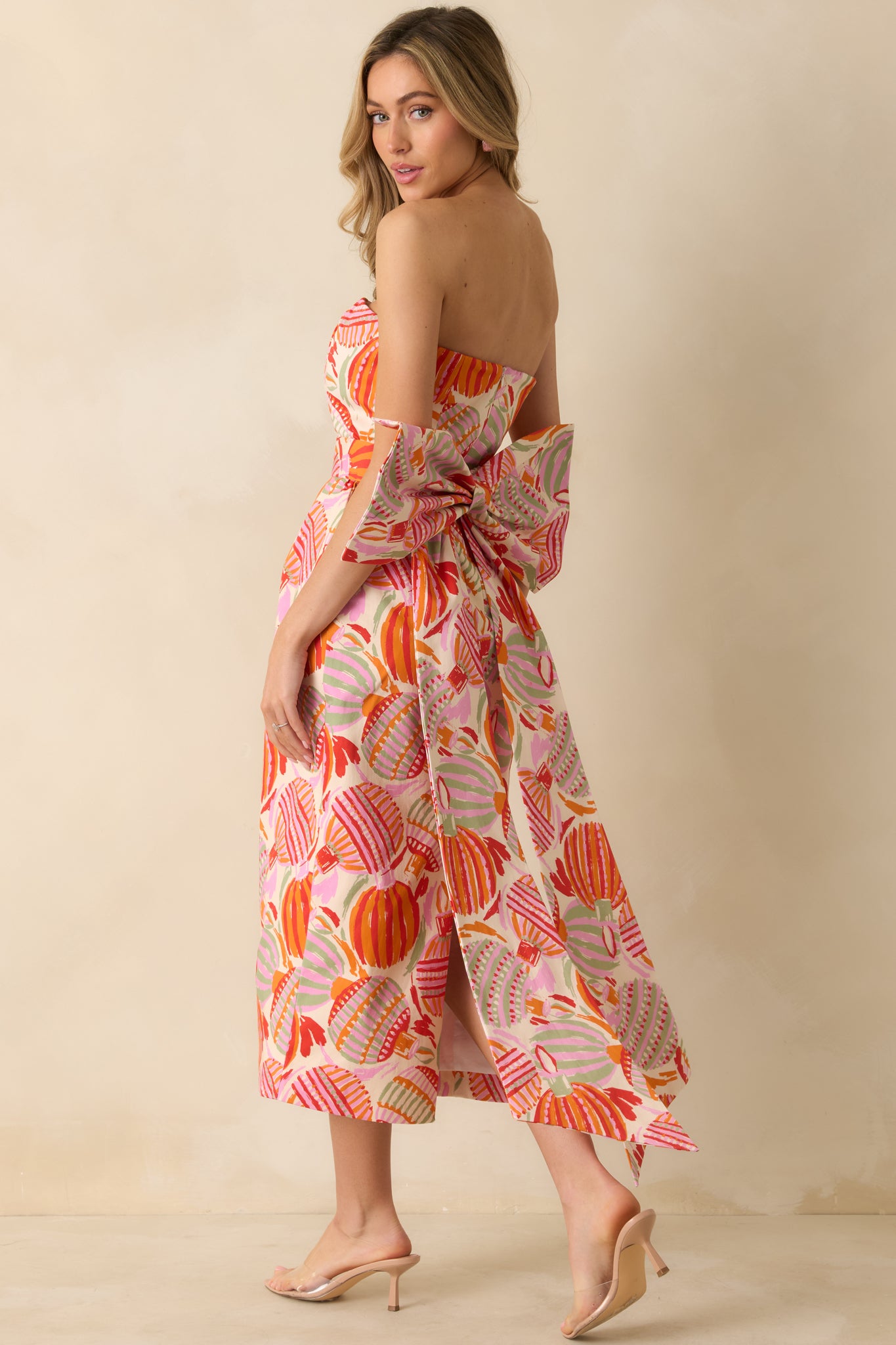The side view showcases the strapless silhouette, asymmetric hem, and oversized bow adding volume and dimension to the pink multicolor dress.