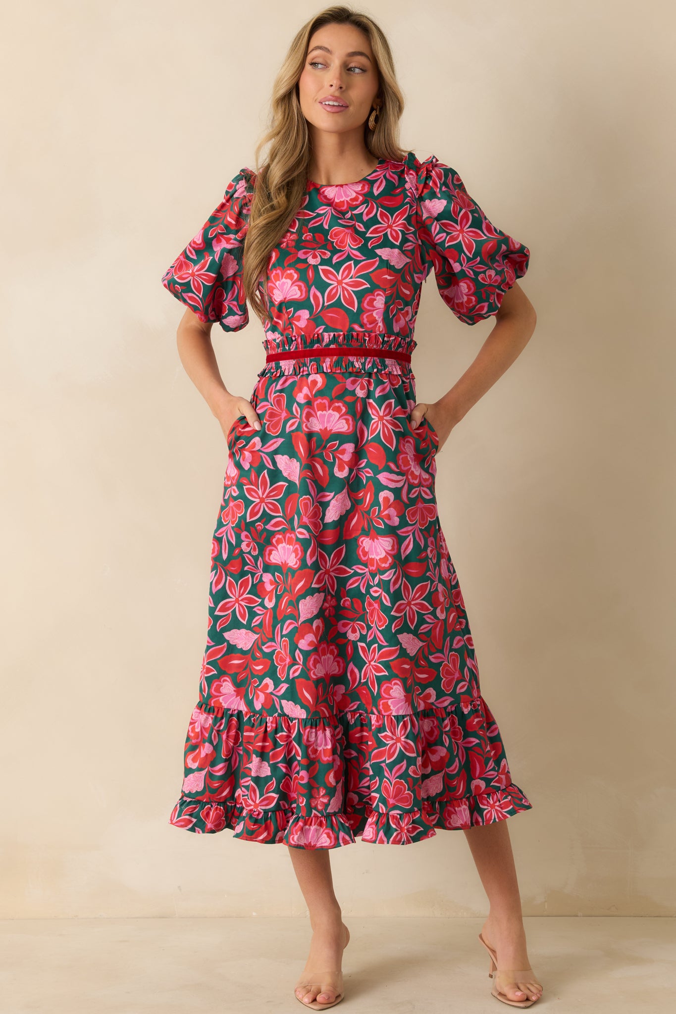 The maxi dress displays its green and pink floral print with puff sleeves and a fitted waist featuring elastic detailing.
