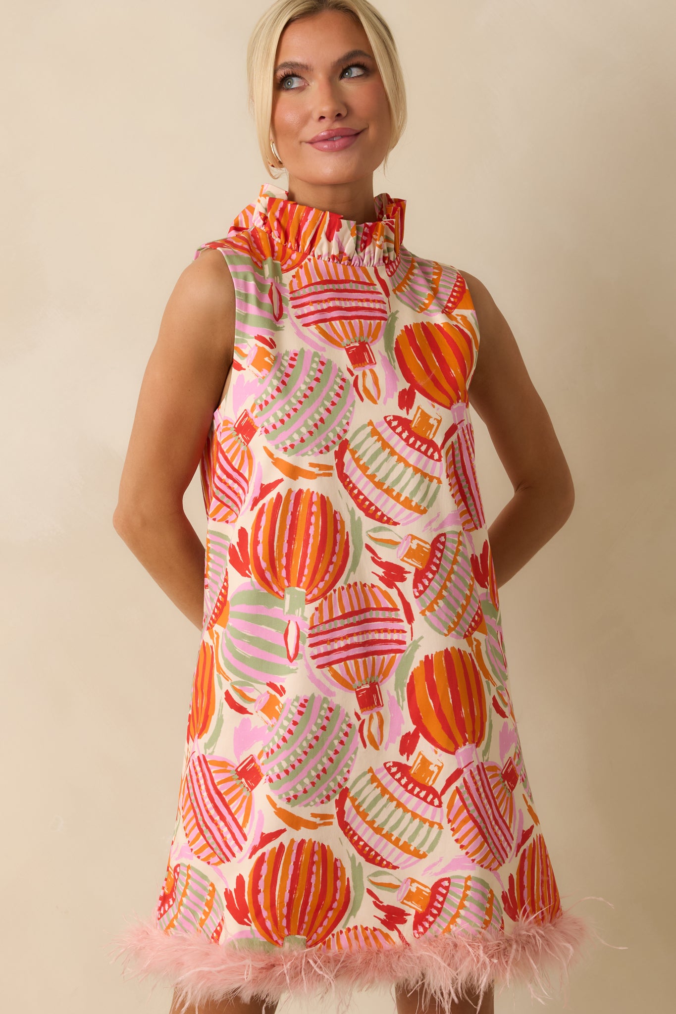 The dress shows its finely textured cotton and vivid ornament motifs with feather trim adding a playful touch.