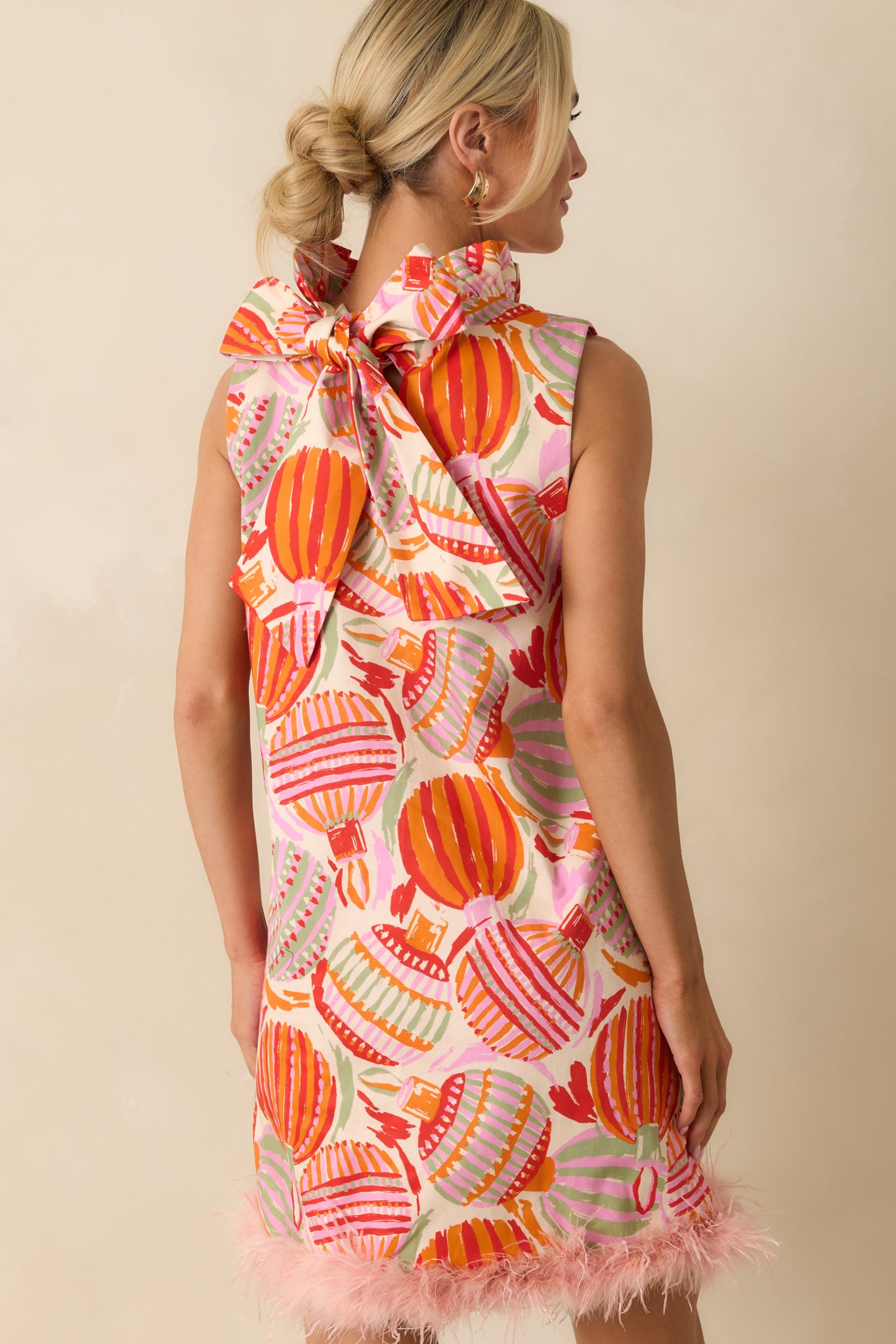 The mini dress at the rear displays its ornamental print, smooth silhouette, and a concealed zipper framed by full lining.