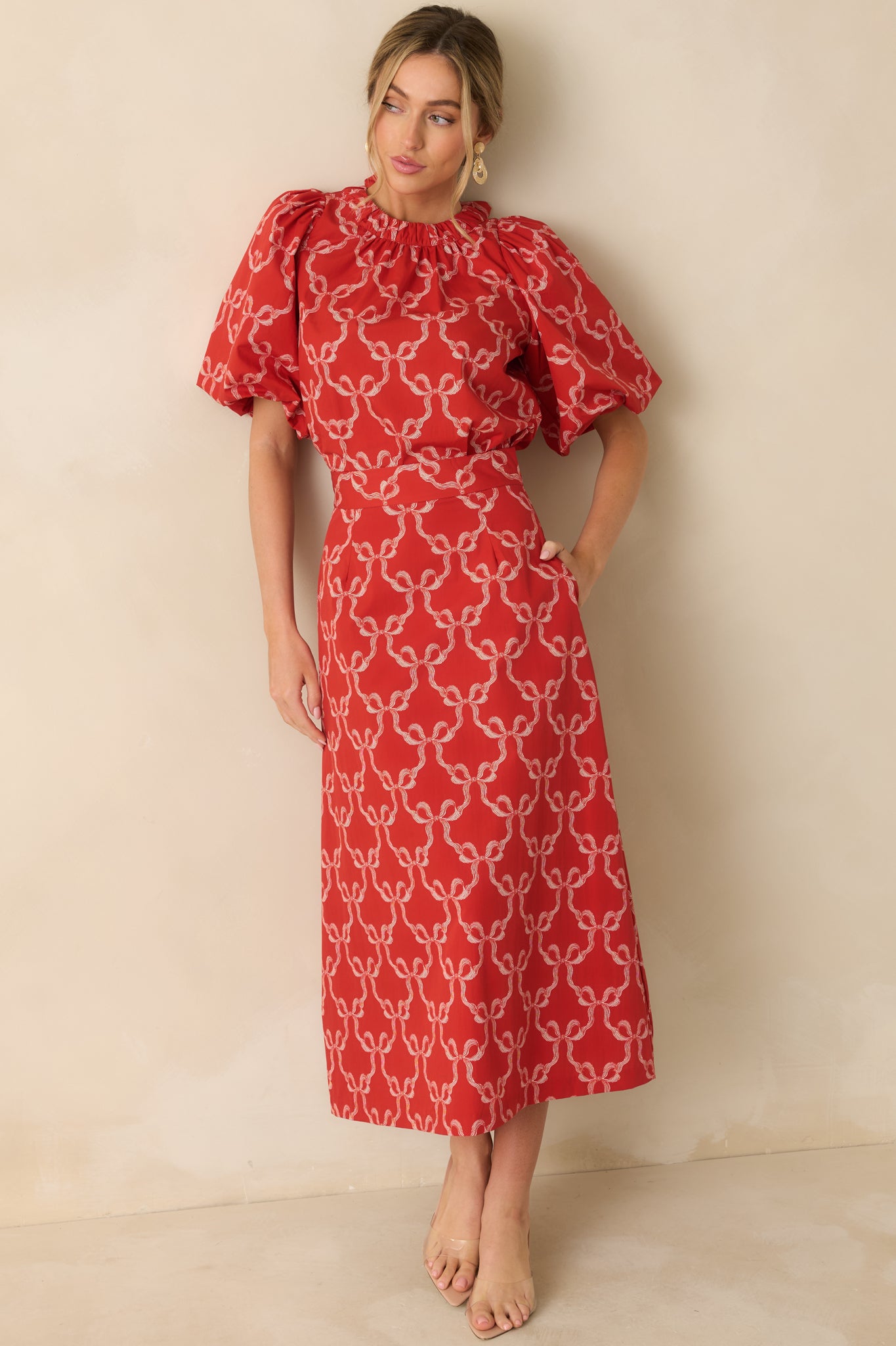 The red blouse shows its allover white bow print, gathered crew neckline, and easy relaxed silhouette.