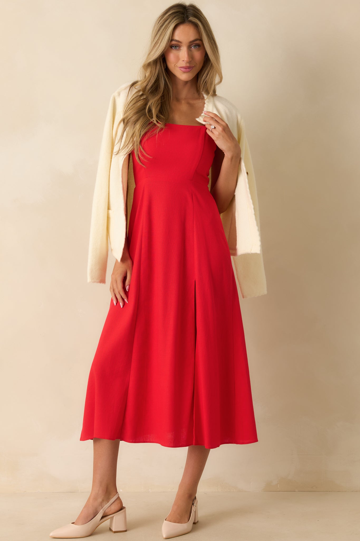 Red midi dress with a square neckline, smocked sleeves, fitted bodice, and a flowy skirt with a leg slit.