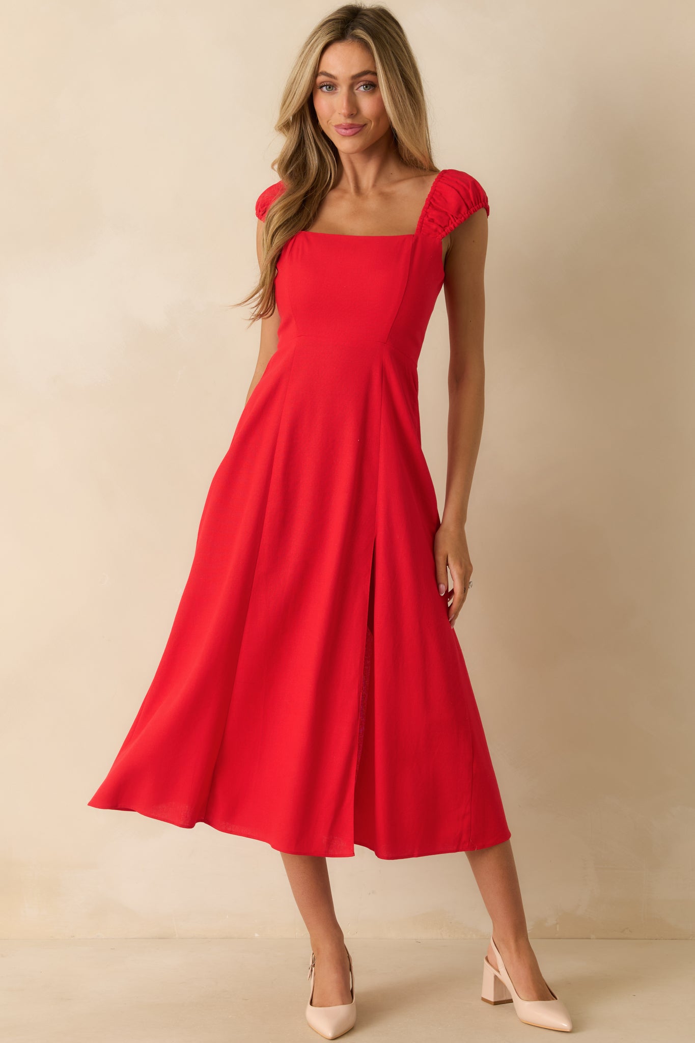 Red midi dress with smocked sleeve detailing, square neckline, and a gently flared skirt with slit accent.