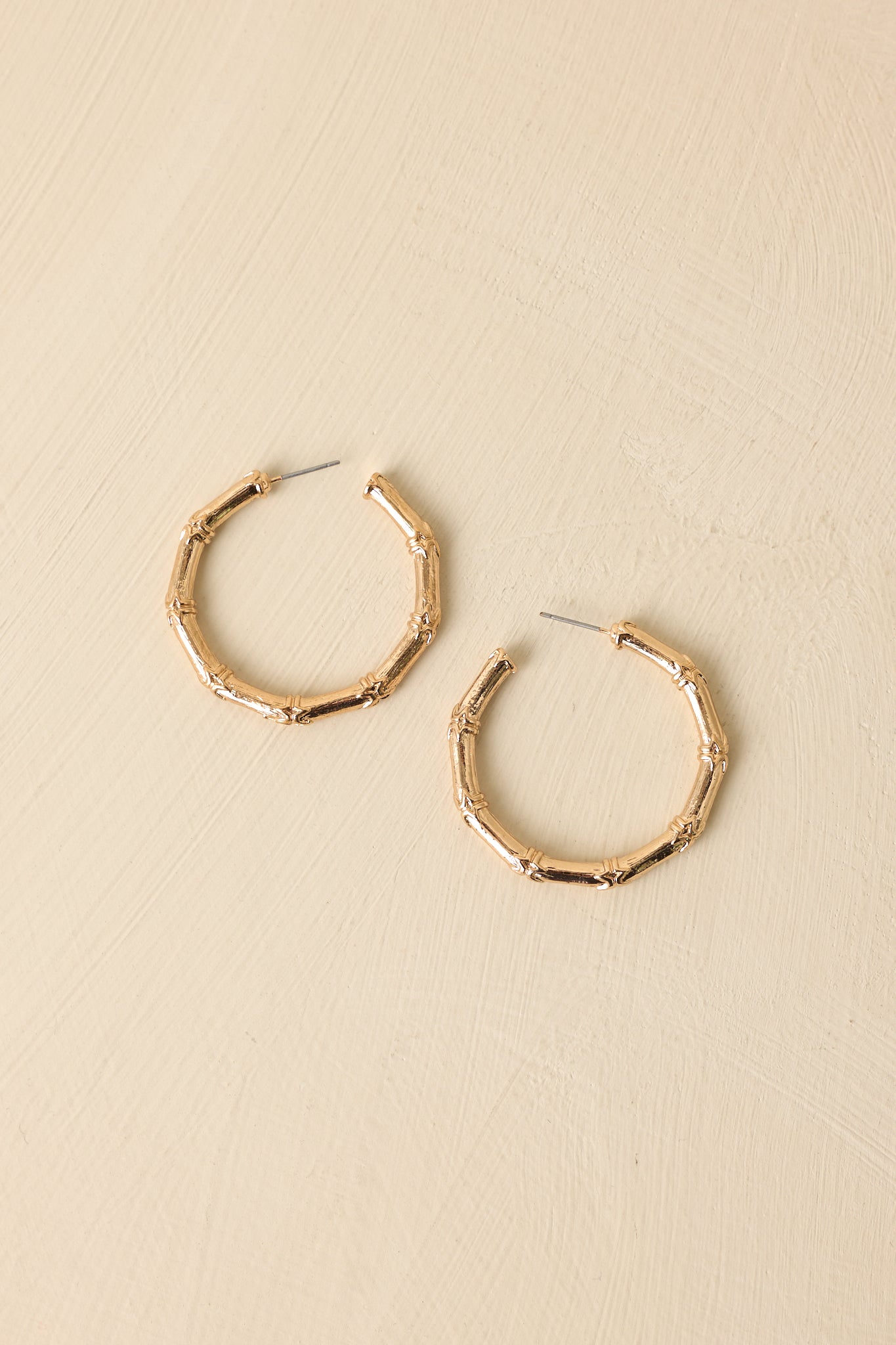 Close-up of gold statement hoop earrings highlighting bamboo-inspired texture and polished gold craftsmanship.