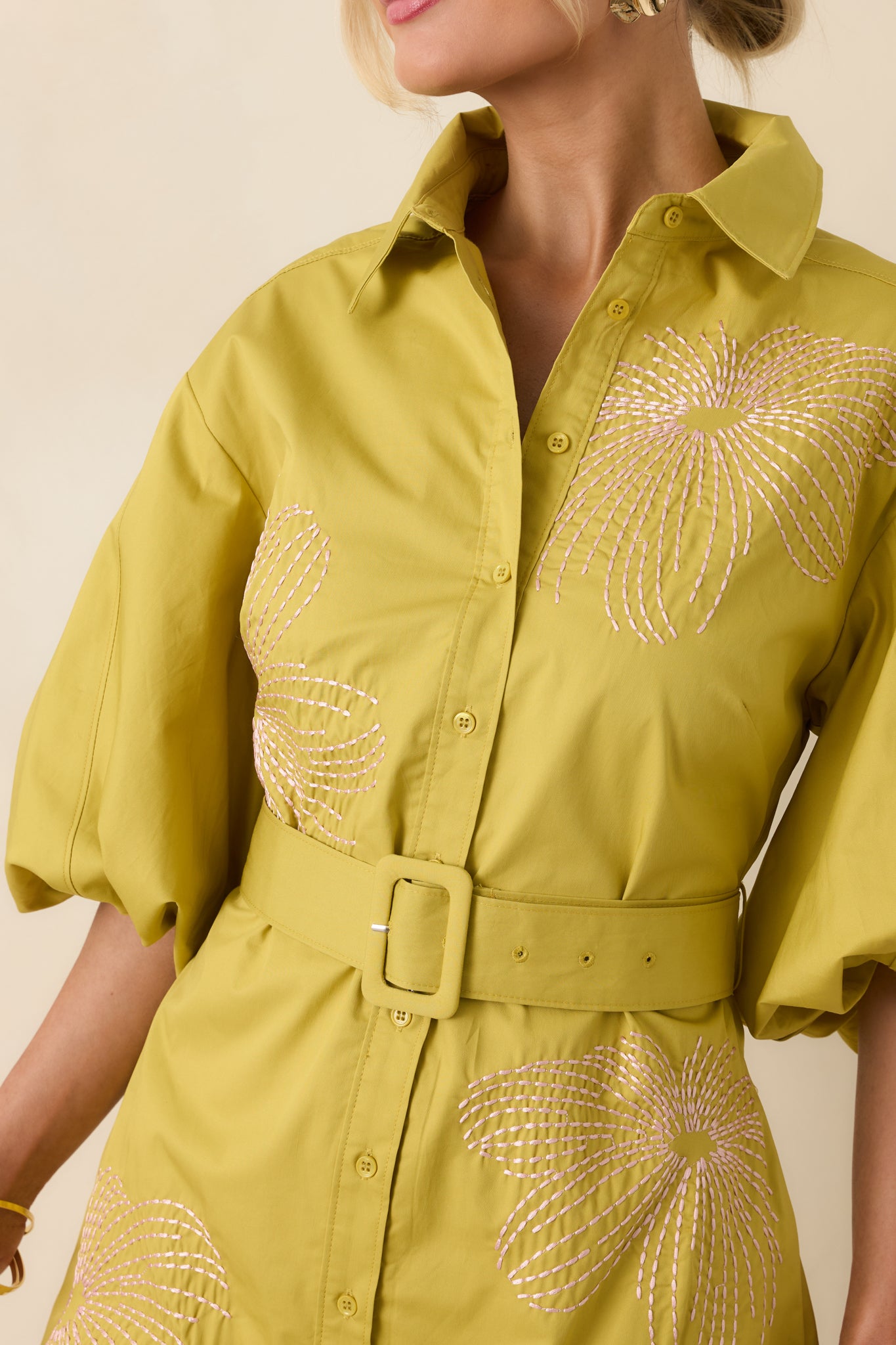 Detailed view of light pink embroidery on cotton fabric with button-front and structured stitching.