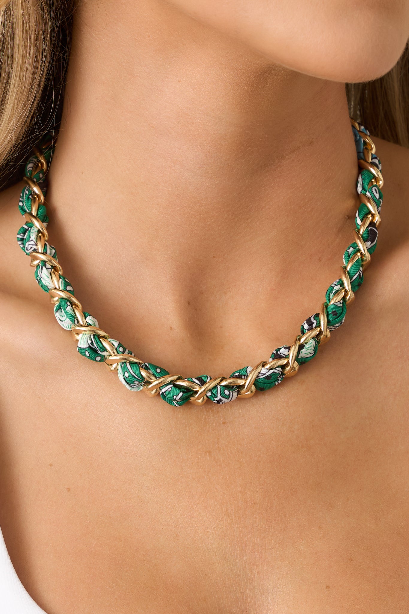 Close-up detail focusing on the intricate weaving of the green patterned fabric through the gold-tone links.