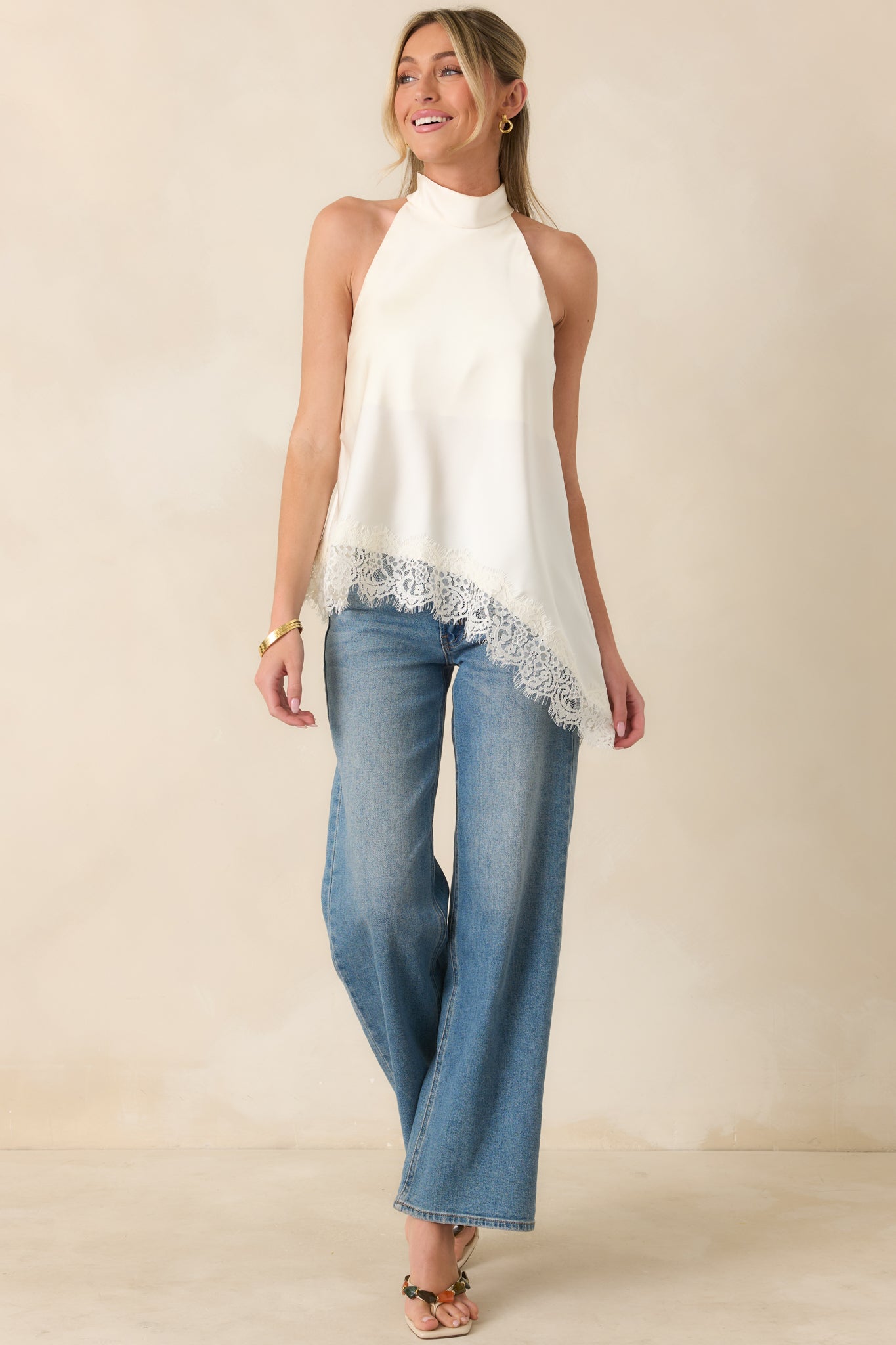 Lightweight ivory woven top with a sleek halter design, elegant drape, and delicate eyelash lace trim accents.
