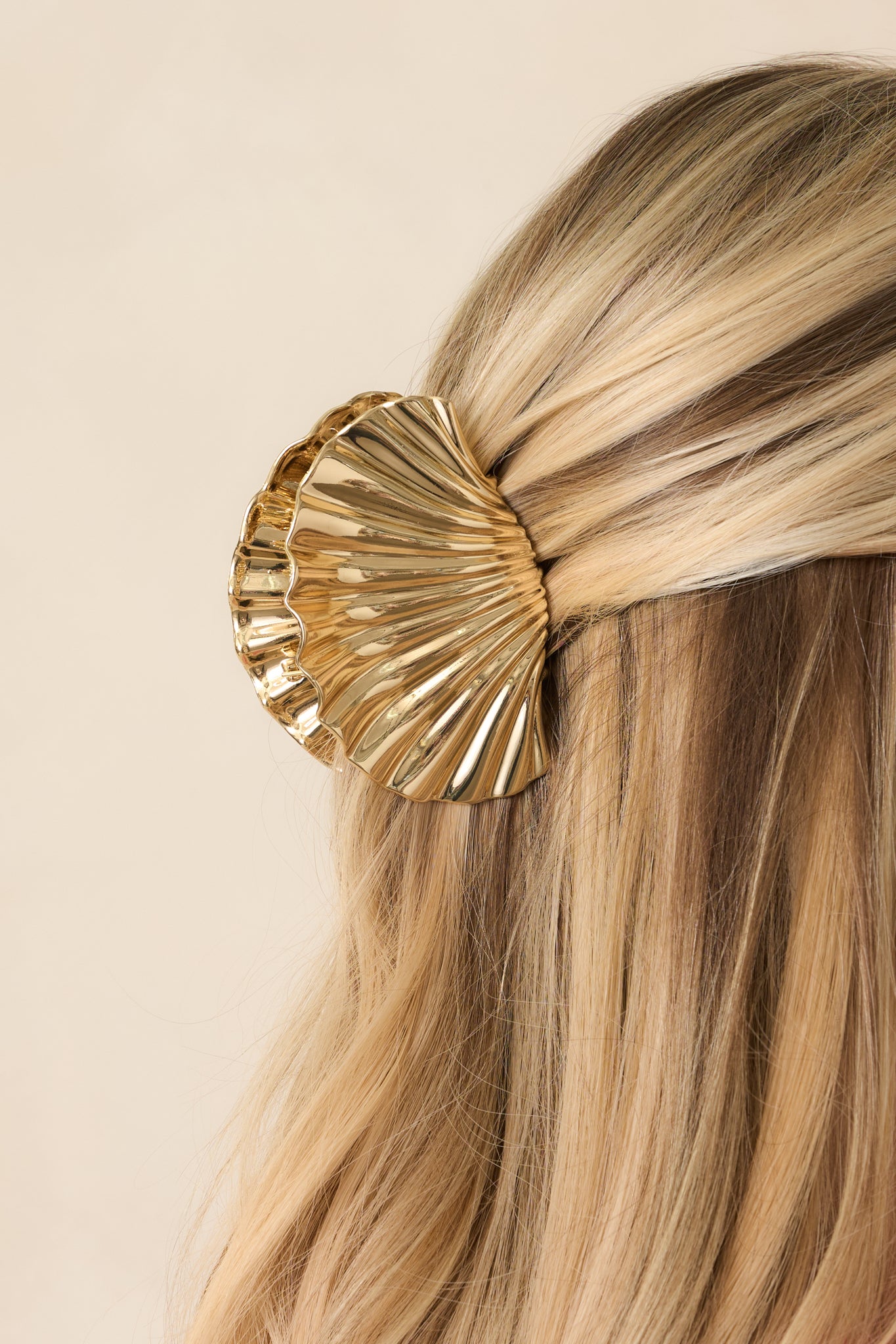 Close-up of gold hair clip showcasing shell-inspired curvature, high-shine finish, and gripping teeth