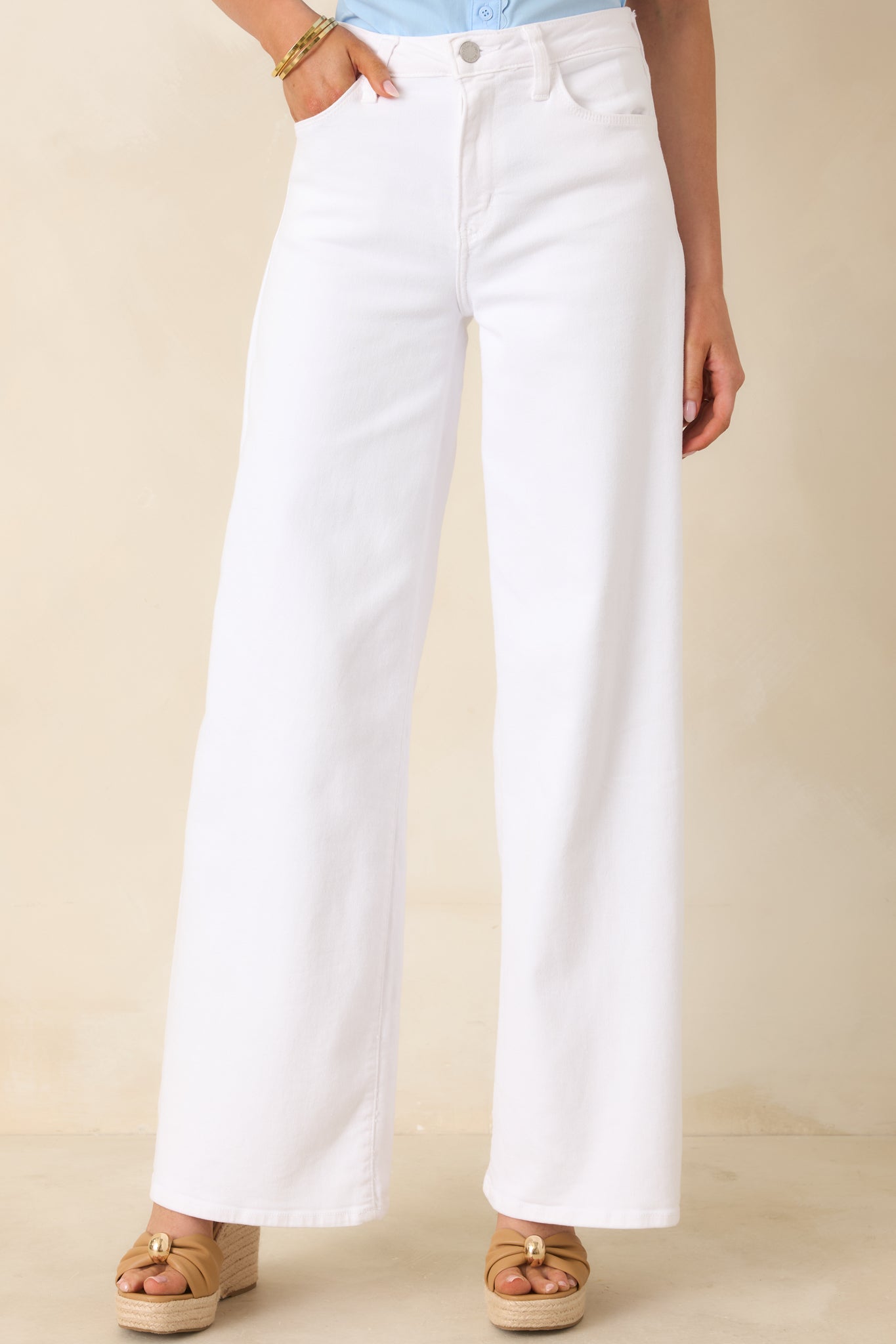 Cropped view of white jeans highlighting the high-rise waistband and smooth front closure.