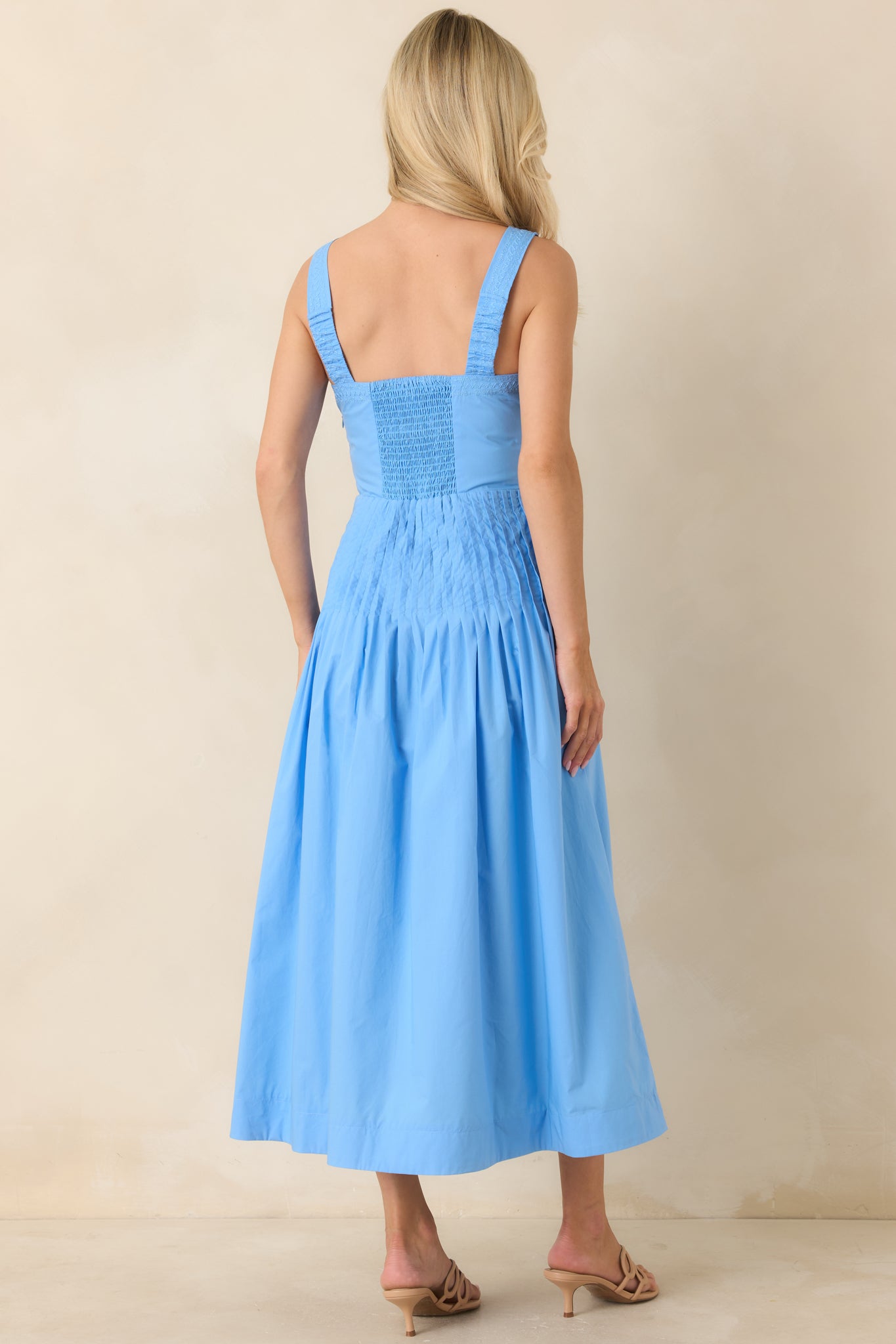 Rear view of cotton dress with smocked back panel and wide strap construction.