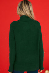 Back view of this sweater that features a cowl turtle neckline, long sleeves with ribbed cuffs, and a bottom hem that tapers in around the hips.