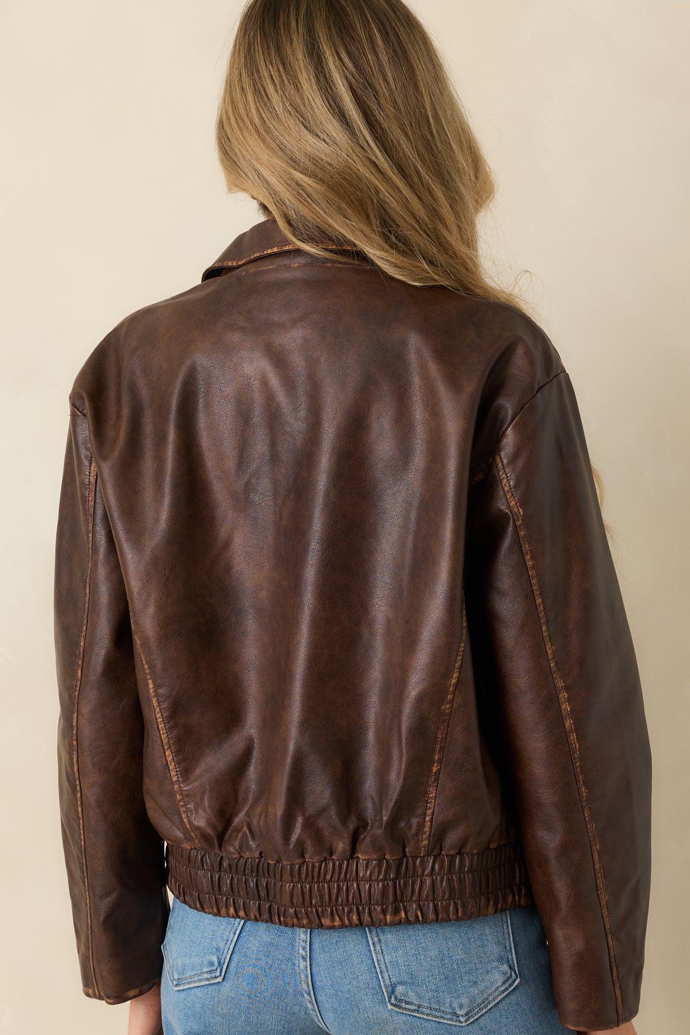 Rear view of the brown faux leather jacket showing the elasticized hem and relaxed shoulder line.