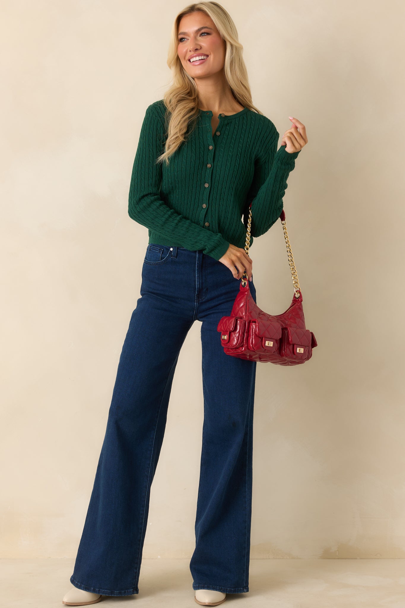 Green cable knit cardigan highlighting the crew neckline and slightly fitted silhouette