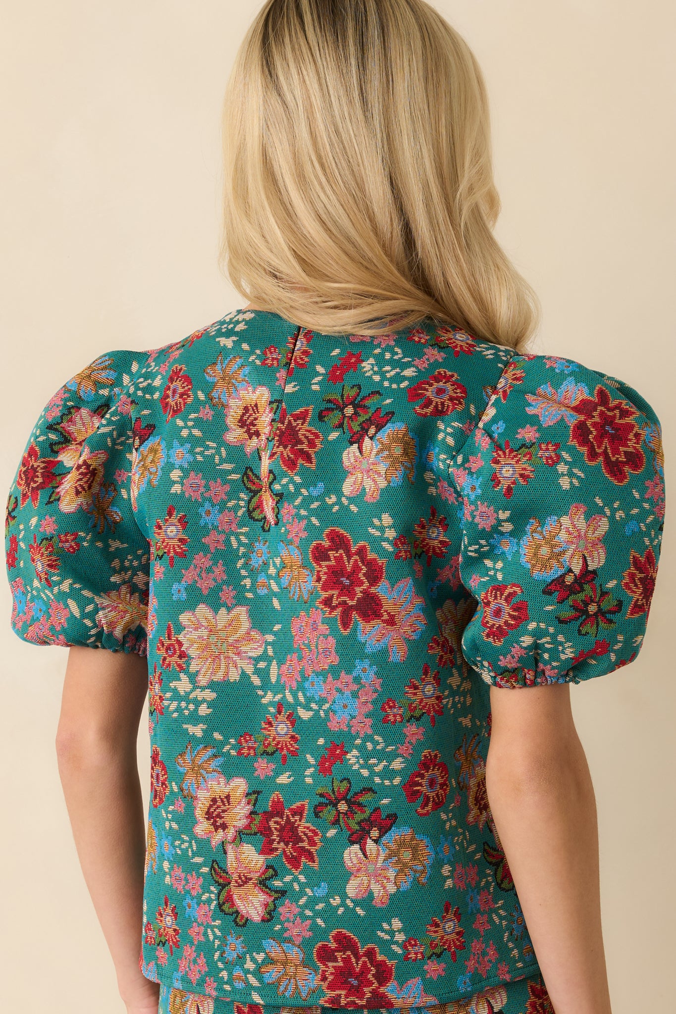 Rear view of the teal-green woven top displaying the hidden back zipper closure and smooth lined back.