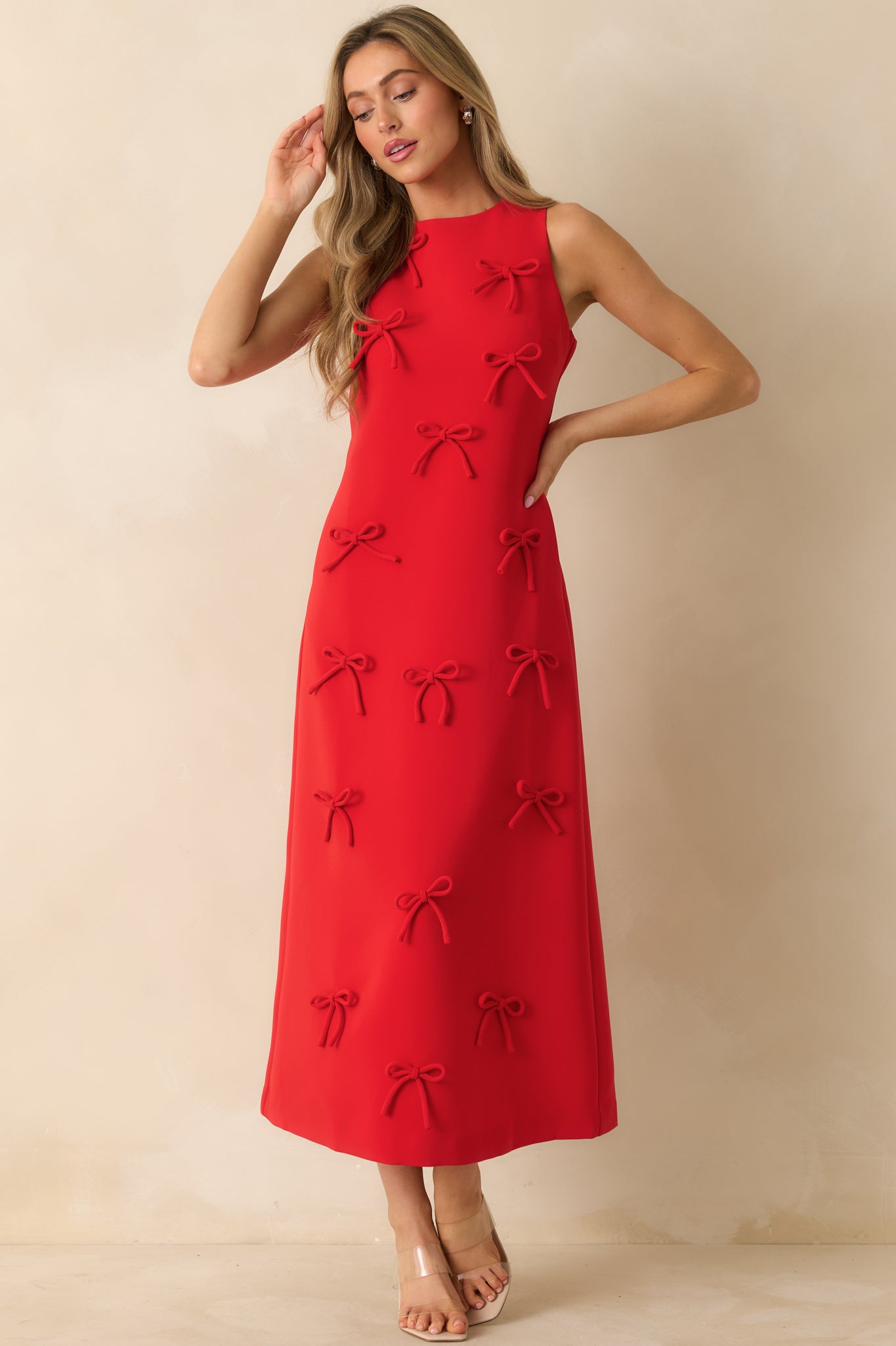 Red sleeveless maxi dress with a relaxed straight fit, bow detailing throughout, and functional side pockets.