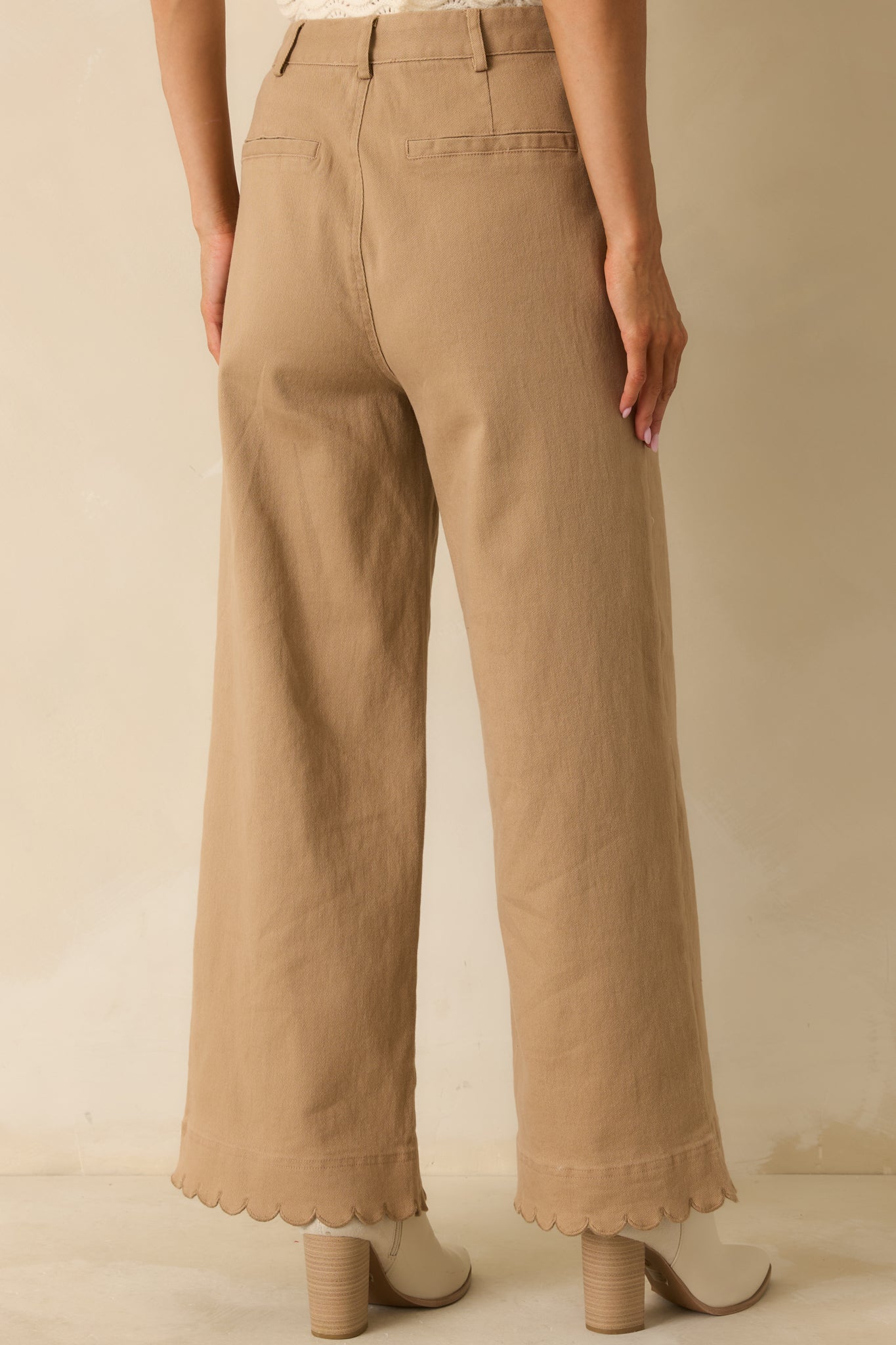 Rear view of camel pants showing back welt pockets and clean wide-leg finish.