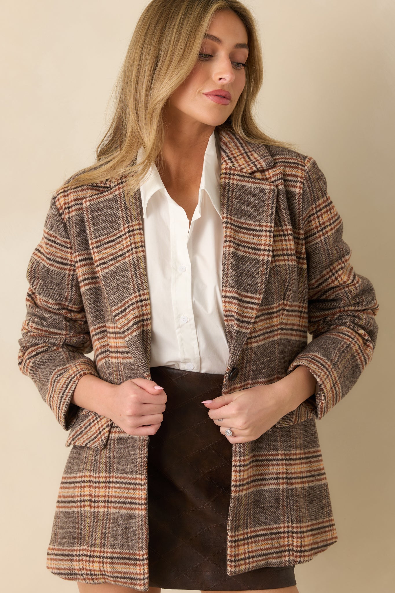 Plaid overcoat in warm brown tones featuring long sleeves, structured tailoring, and an easy, laid-back fit.
