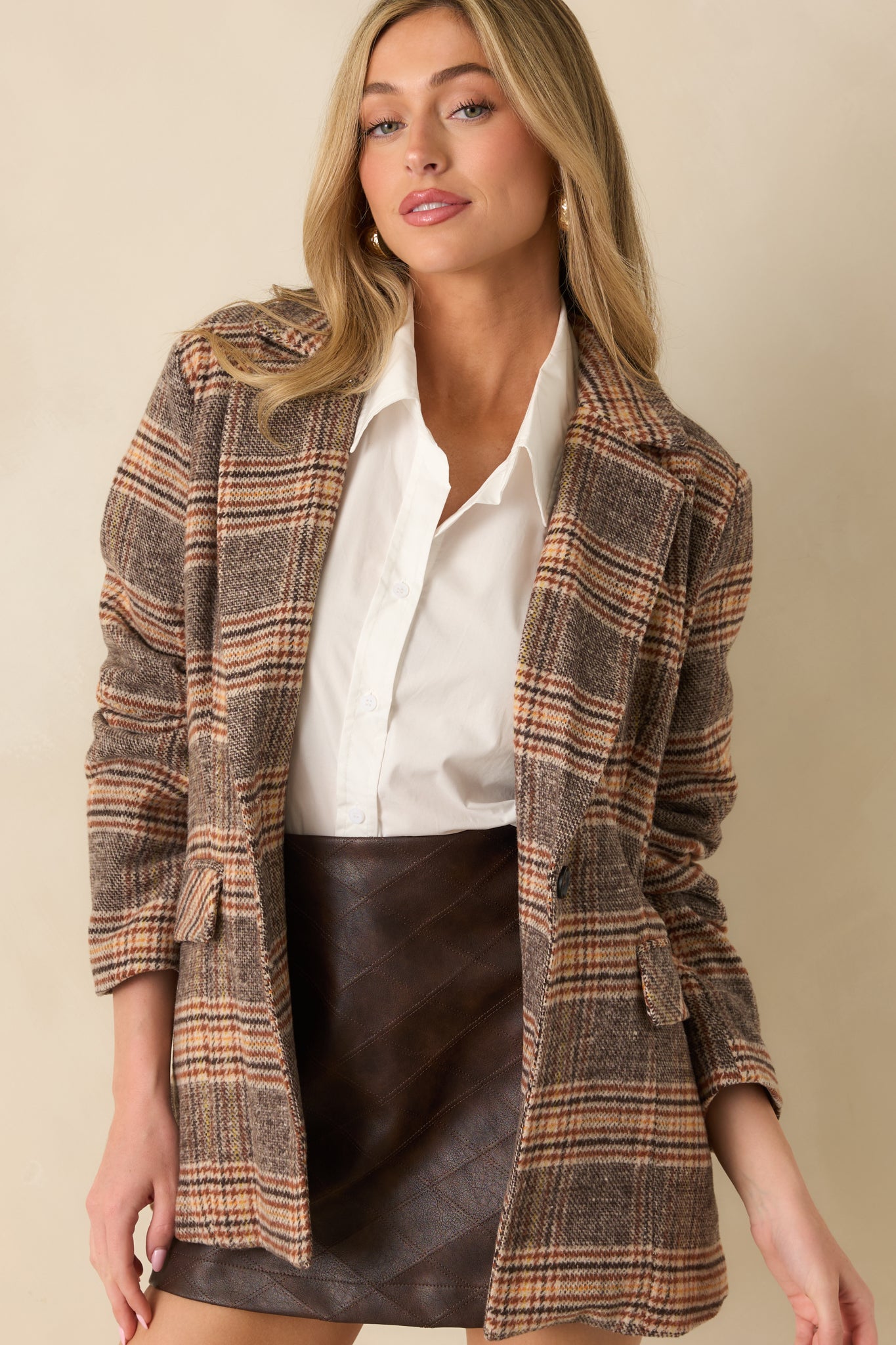 Brown plaid overcoat with a classic collar, front button closure, and relaxed mid-length silhouette.