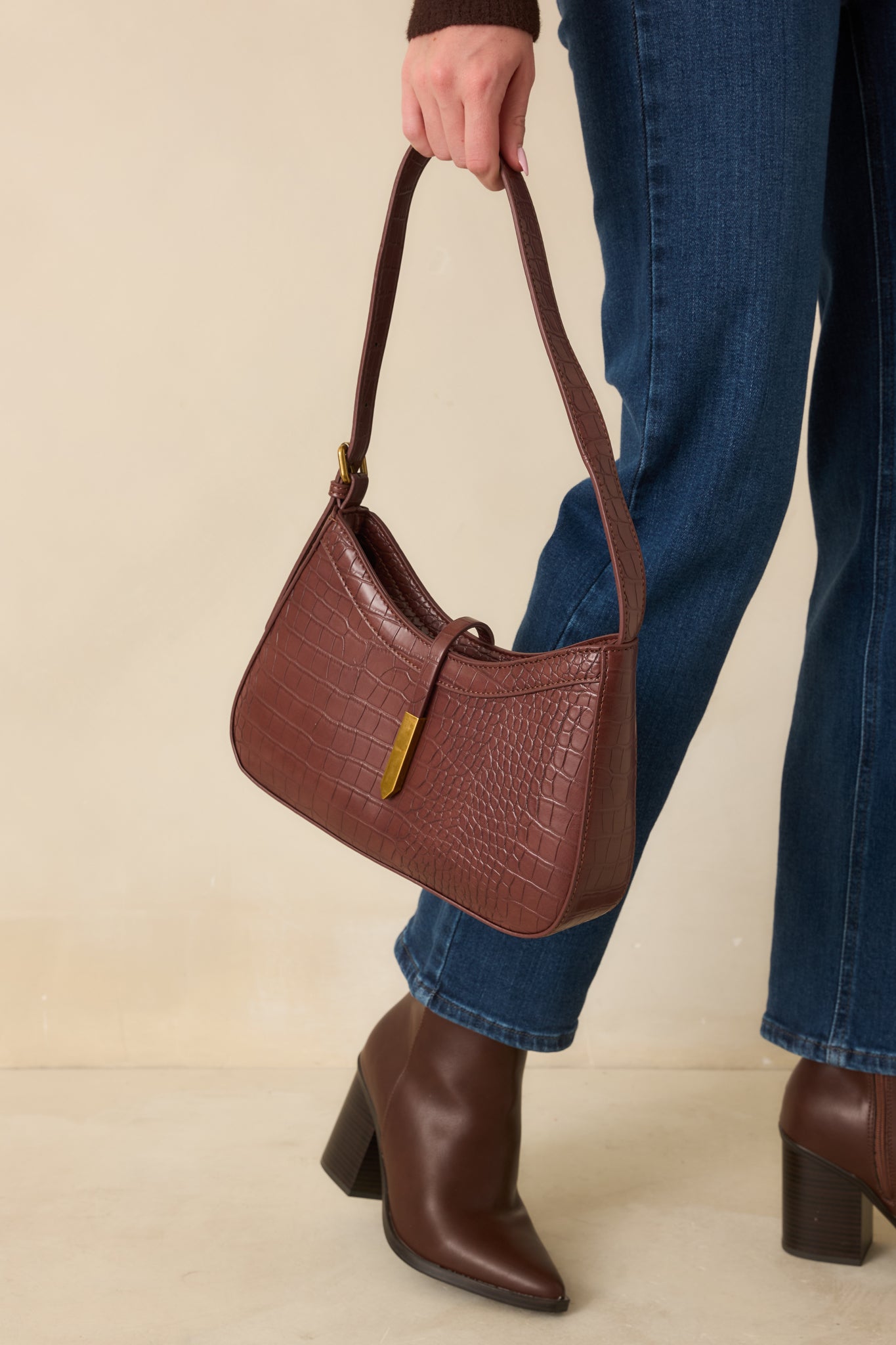Croc-embossed faux leather bag highlighting its smooth shape and gleaming rectangular gold-tipped closure.