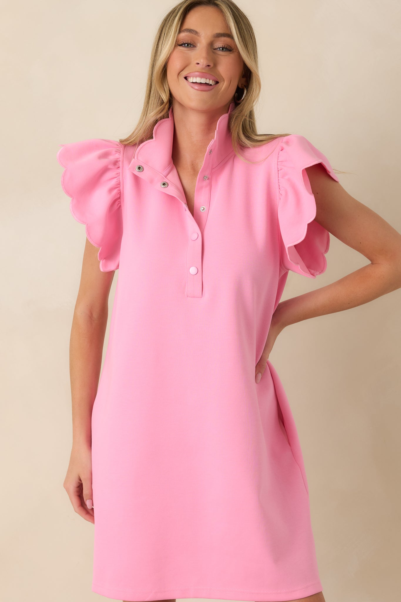 Pink mini dress highlighting scalloped flutter sleeves and structured collared neckline.