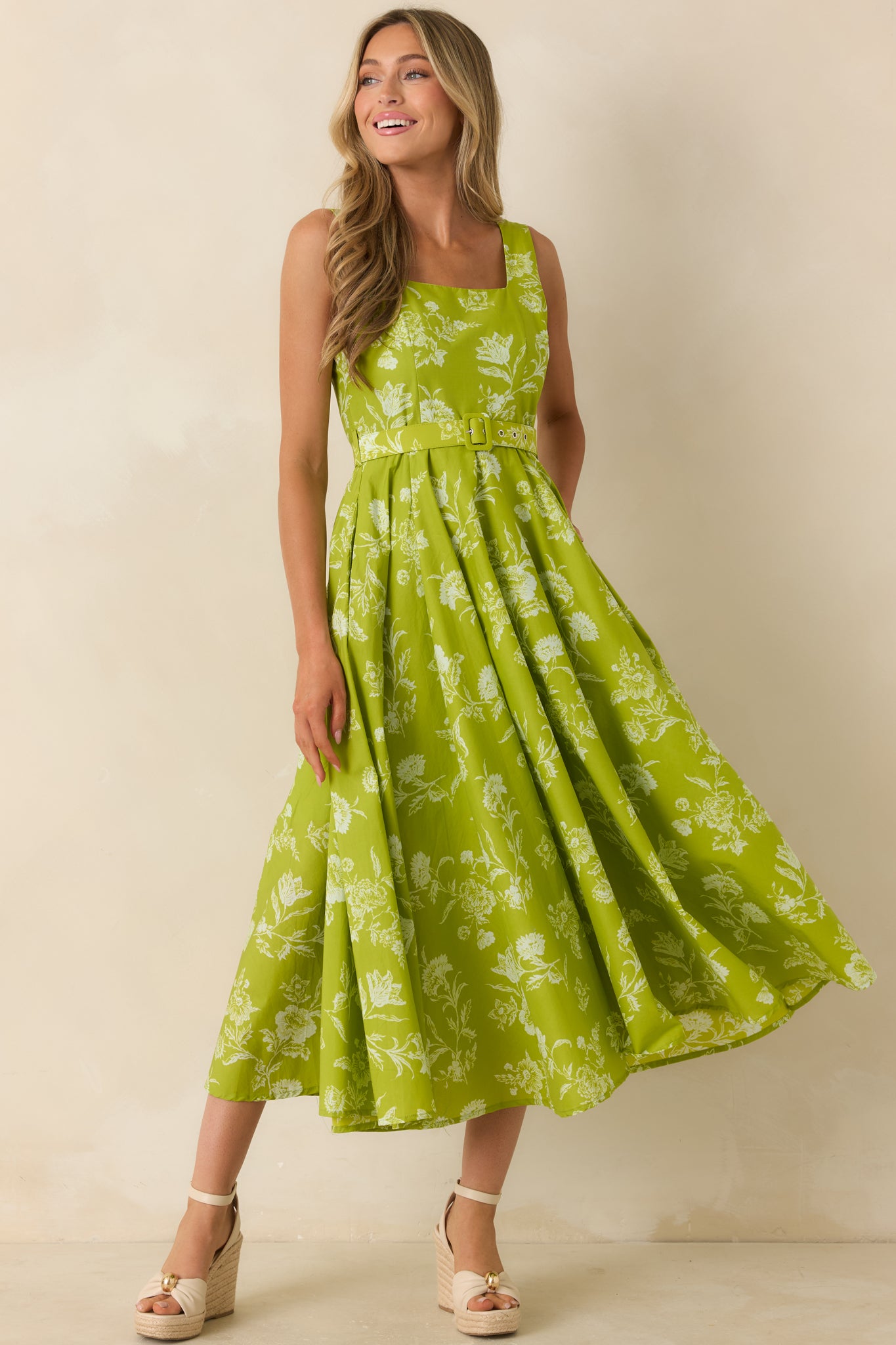 Sleeveless floral midi dress featuring wide straps, a fitted bodice with matching belt, and a full flowing skirt.