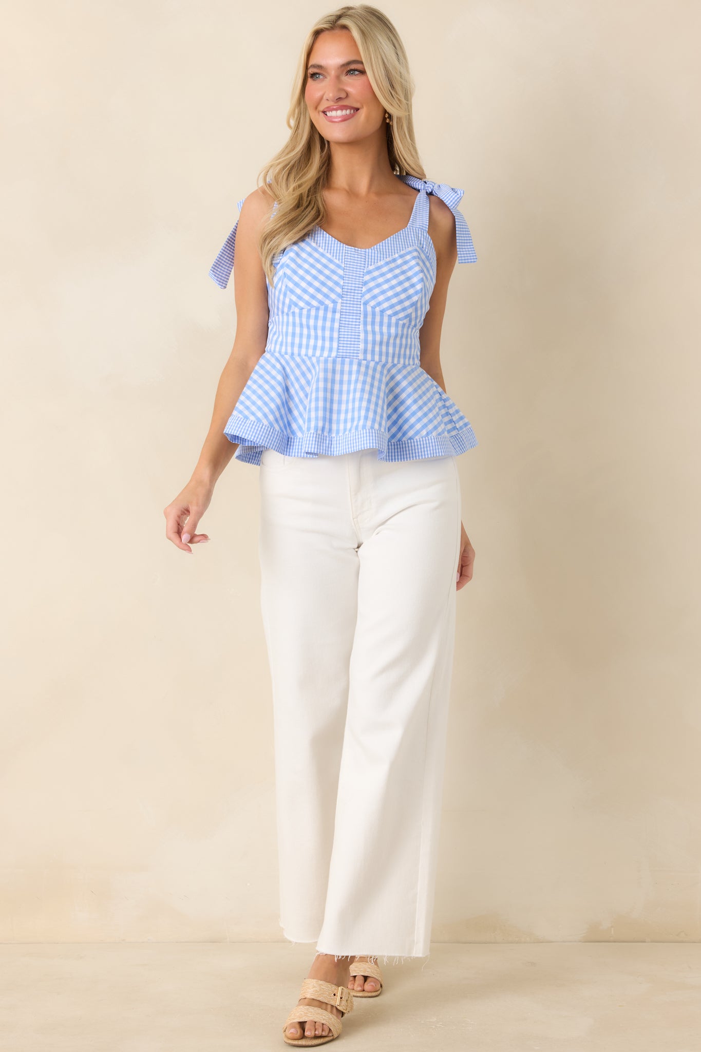 Blue and white gingham cotton peplum top featuring a sweetheart neckline, tie straps, and flared silhouette.