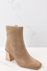Outside view of taupe high heel booties featuring a slightly square toe, and a chunky heel.