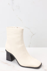Outside view of beige high heel booties featuring a slightly square toe, and a chunky heel.