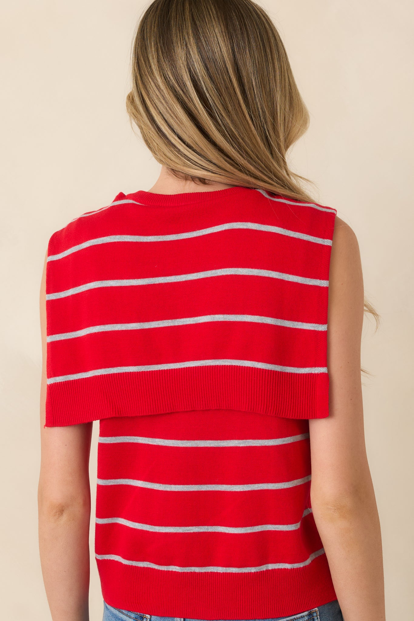 Rear view of red striped sweater tank featuring cape-style back detail and relaxed knit silhouette.

