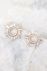 Top view of these earrings that feature gold hardware, a circular design, rhinestone detailing, and a secure post backing.