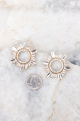 Full view of these earrings that feature gold hardware, a circular design, rhinestone detailing, and a secure post backing.