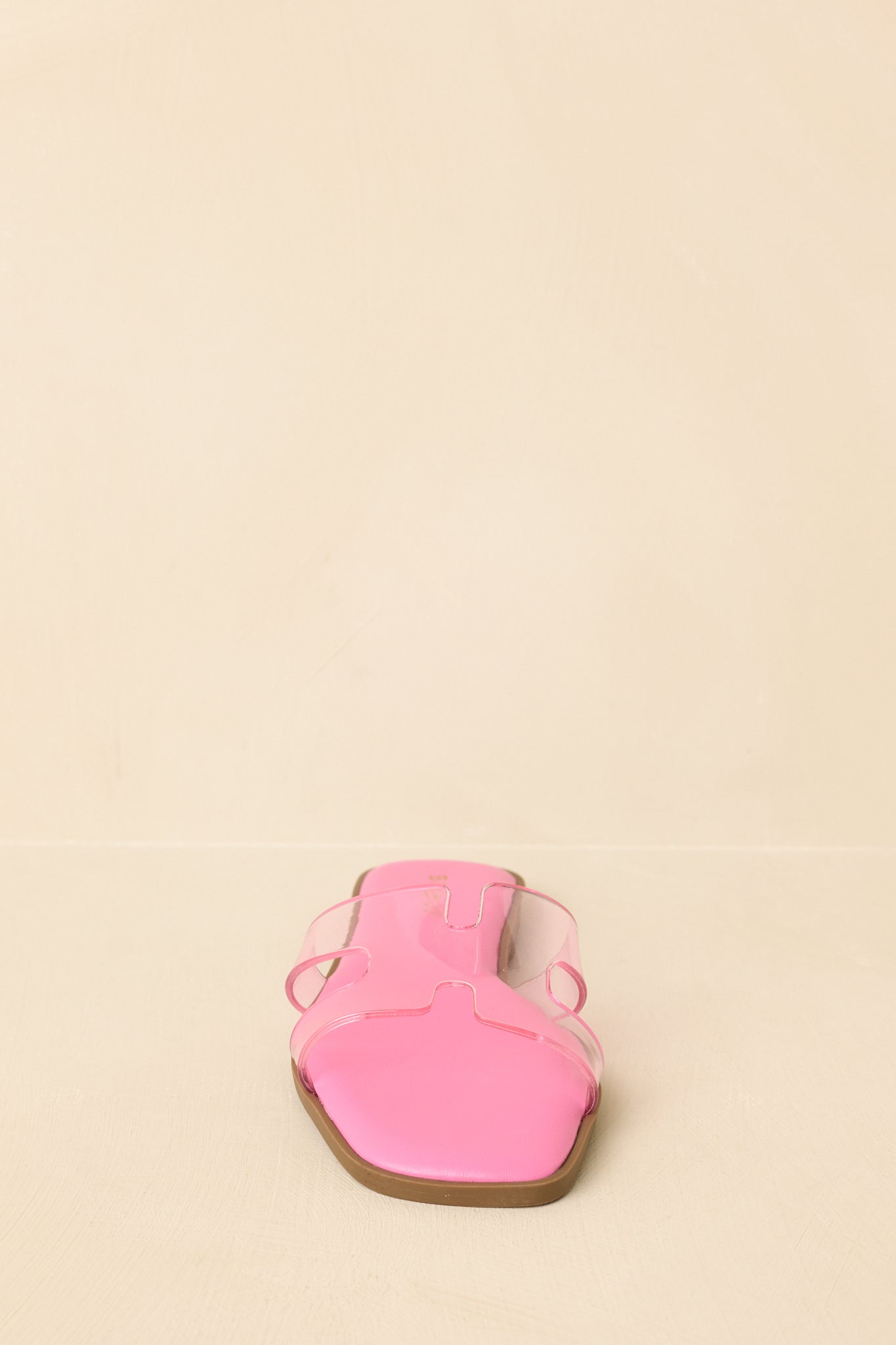Front view of pink slide sandals displaying open square toe and wide clear strap.