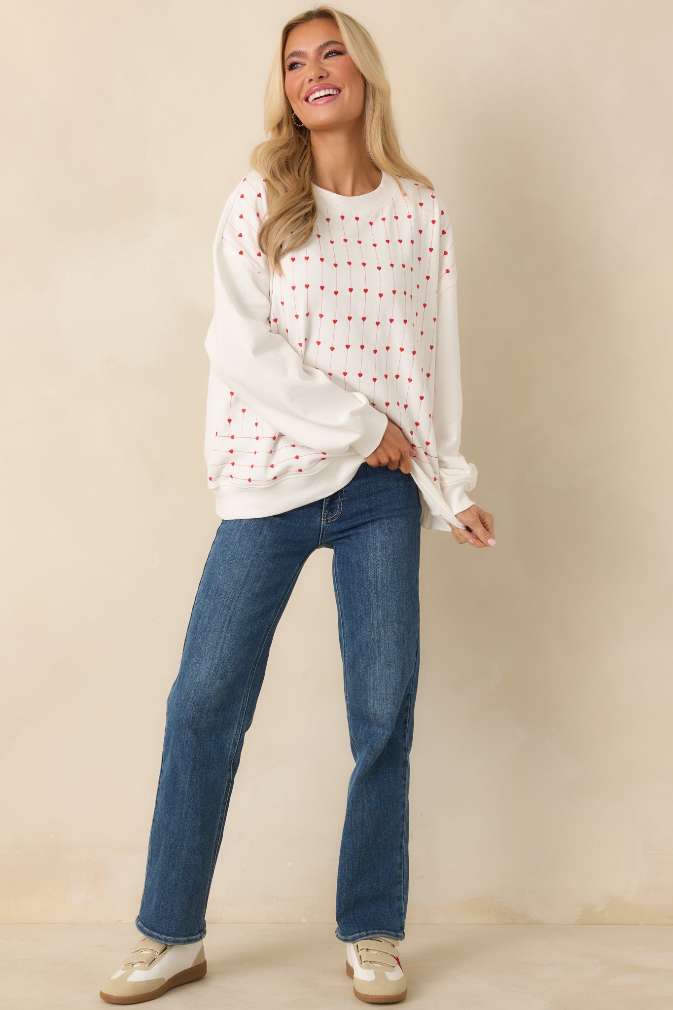 This white crewneck sweatshirt is covered in neat vertical rows of embroidered hearts across the front, creating a textured, patterned look.