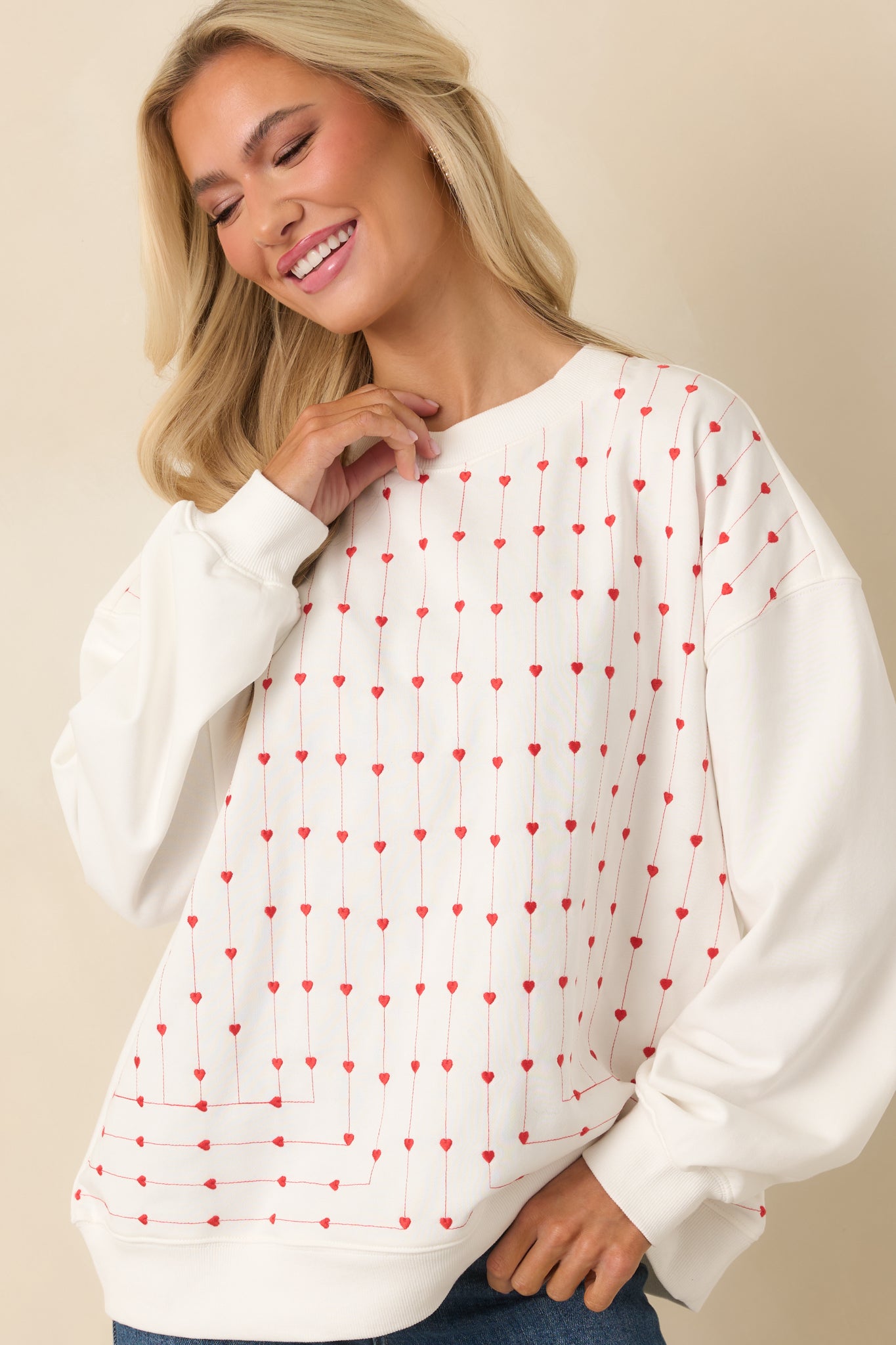 Relaxed-fit white crewneck sweatshirt featuring evenly spaced vertical heart embroidery down the front panel, paired with ribbed hem detailing.