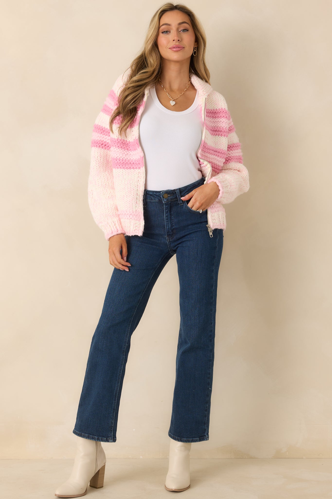 Chunky knit sweater jacket with pink and ivory horizontal stripes, a zip-up front closure, long sleeves, and a cozy collar neckline.