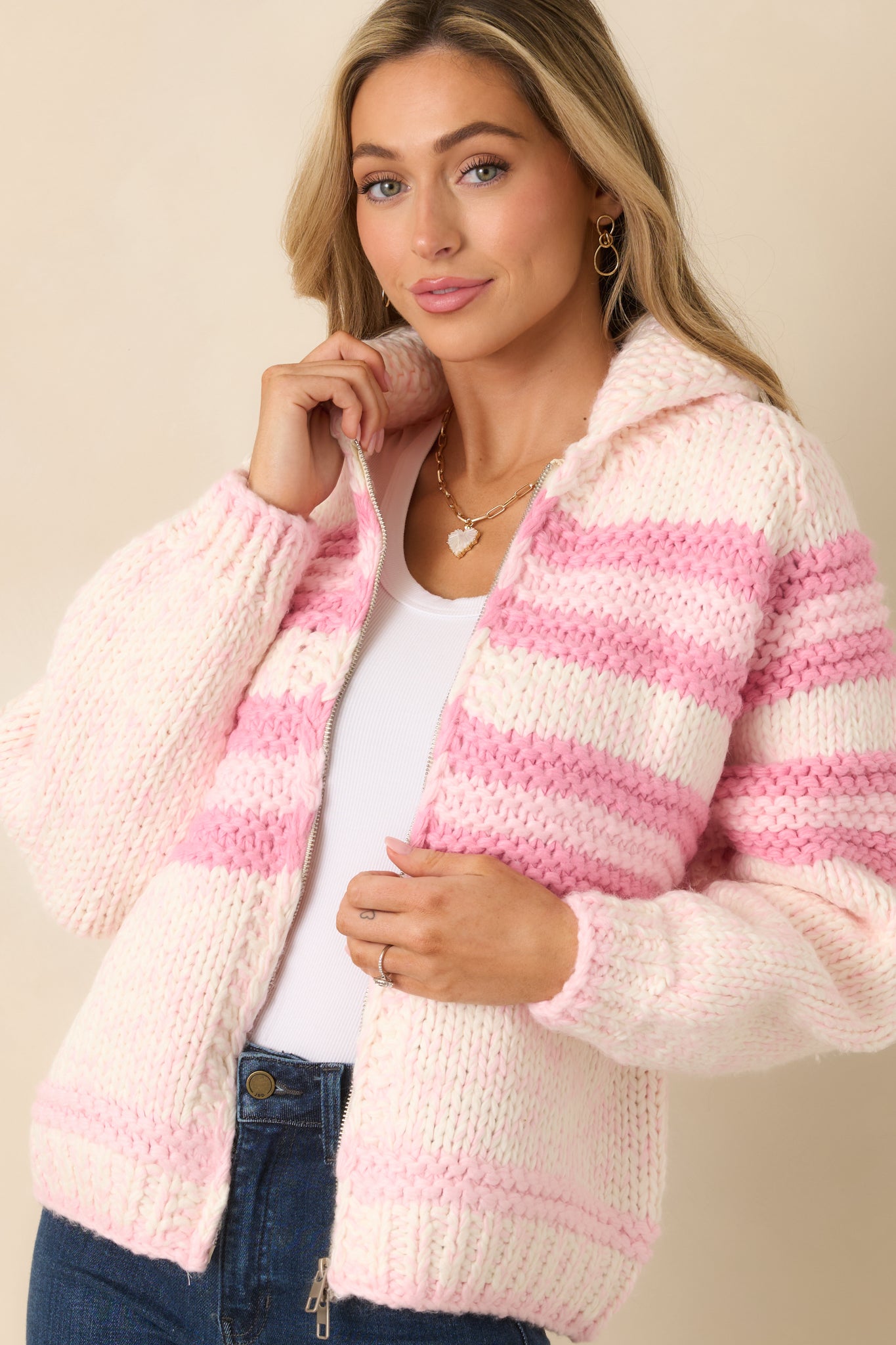 Zoomed look at the sweater's ribbed knit trim along the zipper placket with alternating pink and ivory stripes.