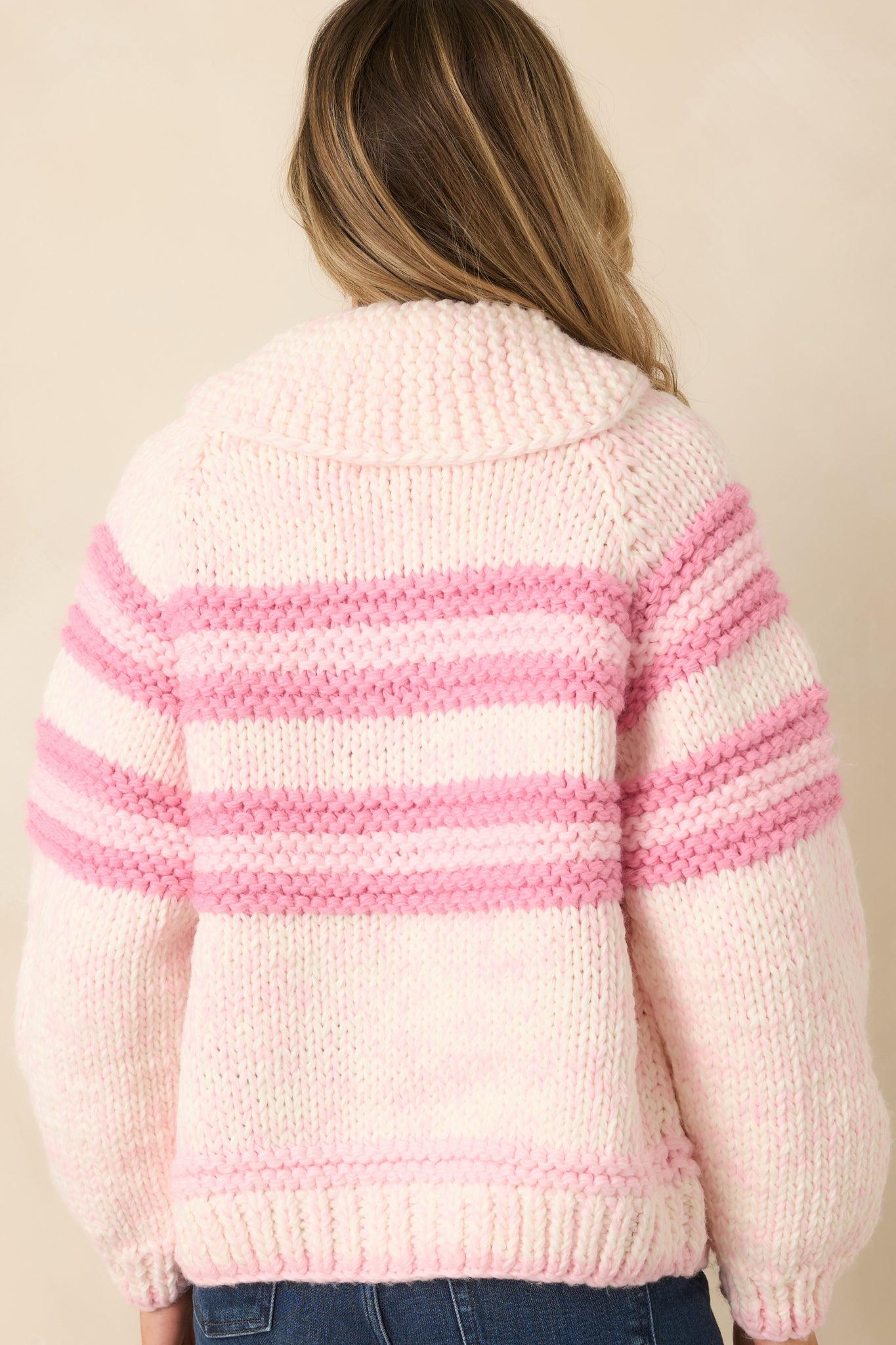 Rear of the chunky knit cardigan showing continuous pink and ivory stripes and ribbed knit texture across the back panel.