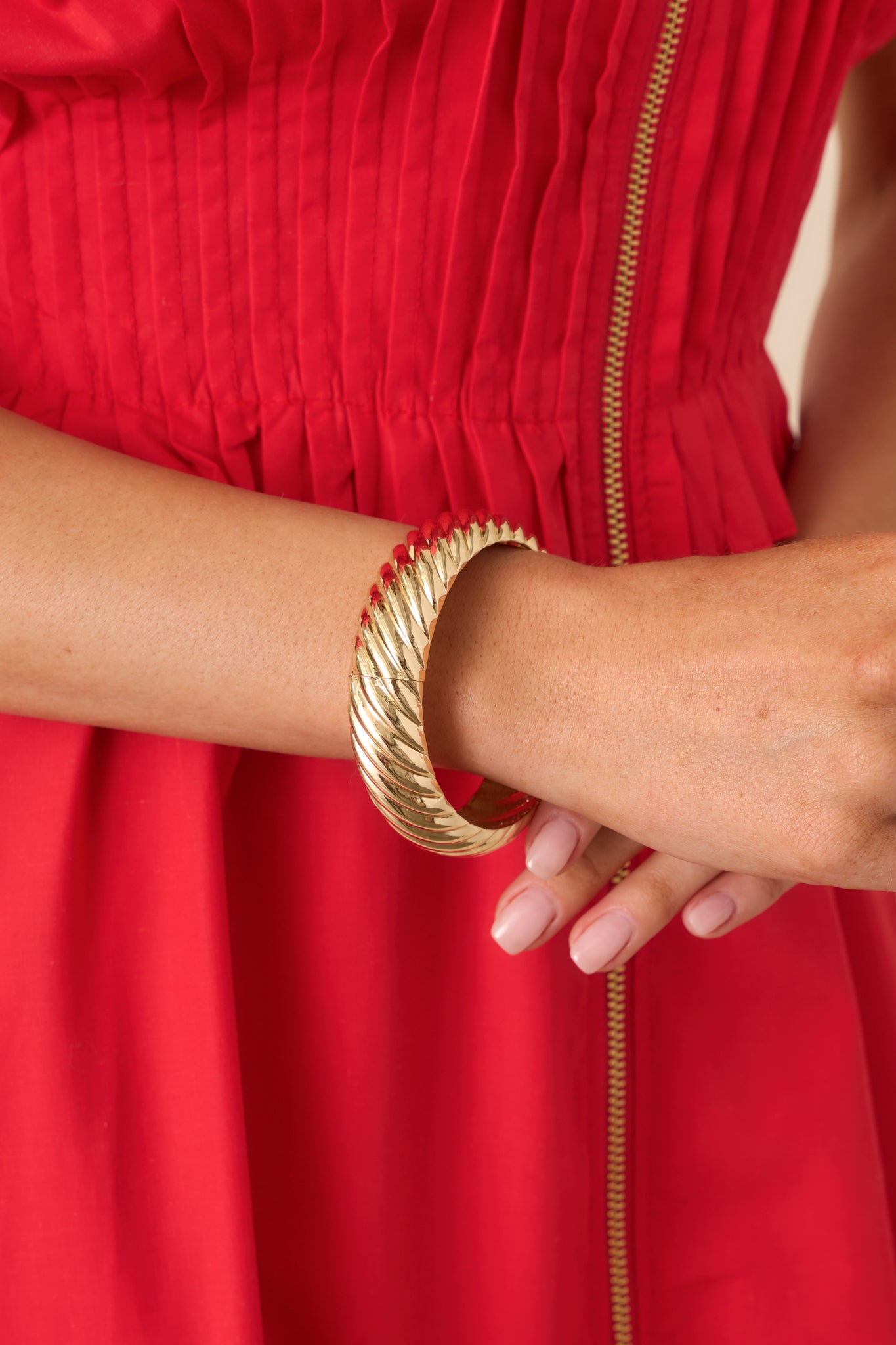 Close view of the twisted gold texture and hinge detail on the high-shine bangle.