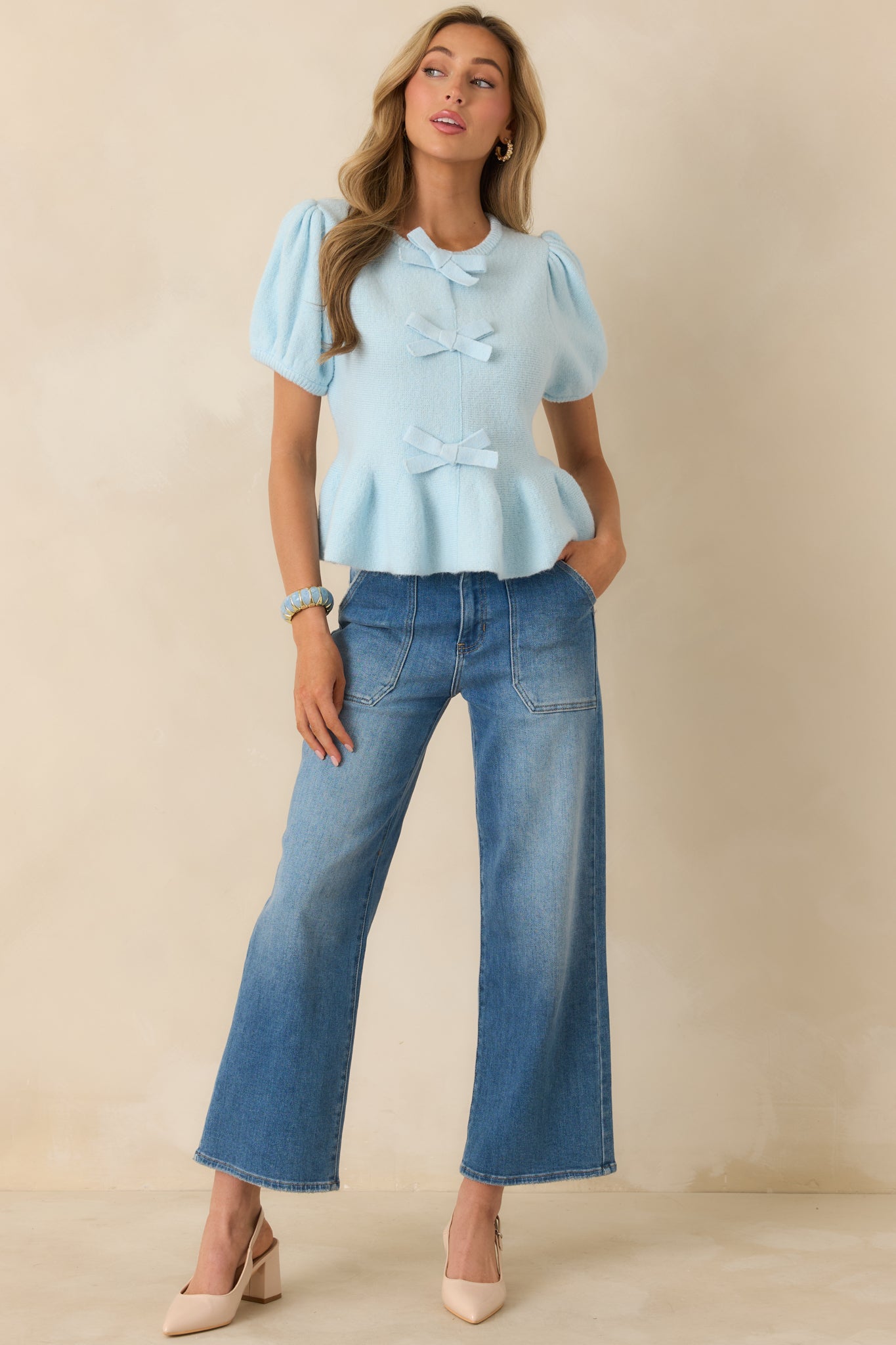 Fitted light blue knit top with gentle stretch, short puff sleeves, and a subtle peplum flare.